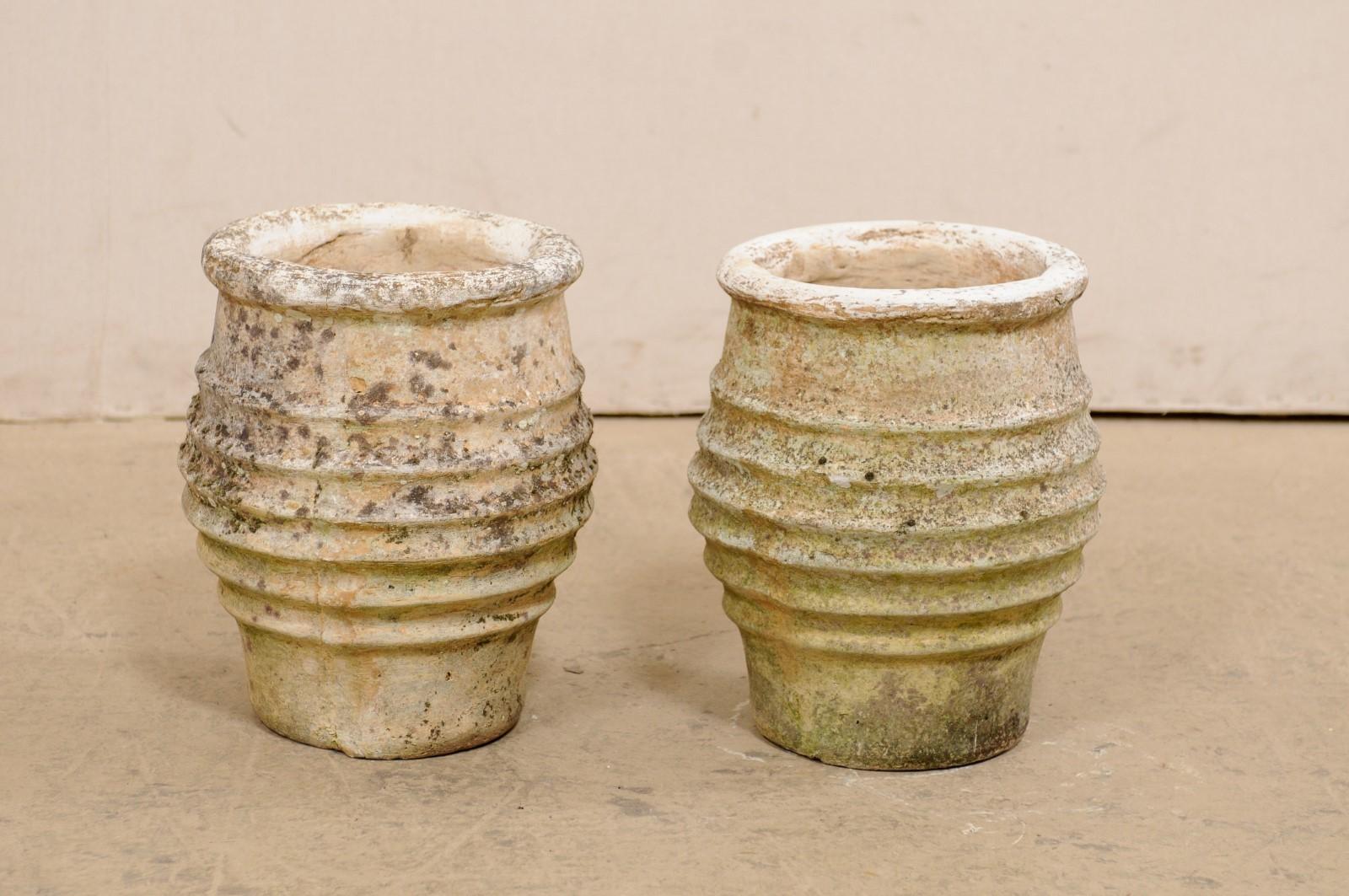 A Spanish pair of cast-stone pots from the 19th century. This pair of antique vessels from Spain, created from cast-stone, are round-shaped, with a thick and pronounced lip at top, a nicely ribbed texture around the perimeter of their bodies, and