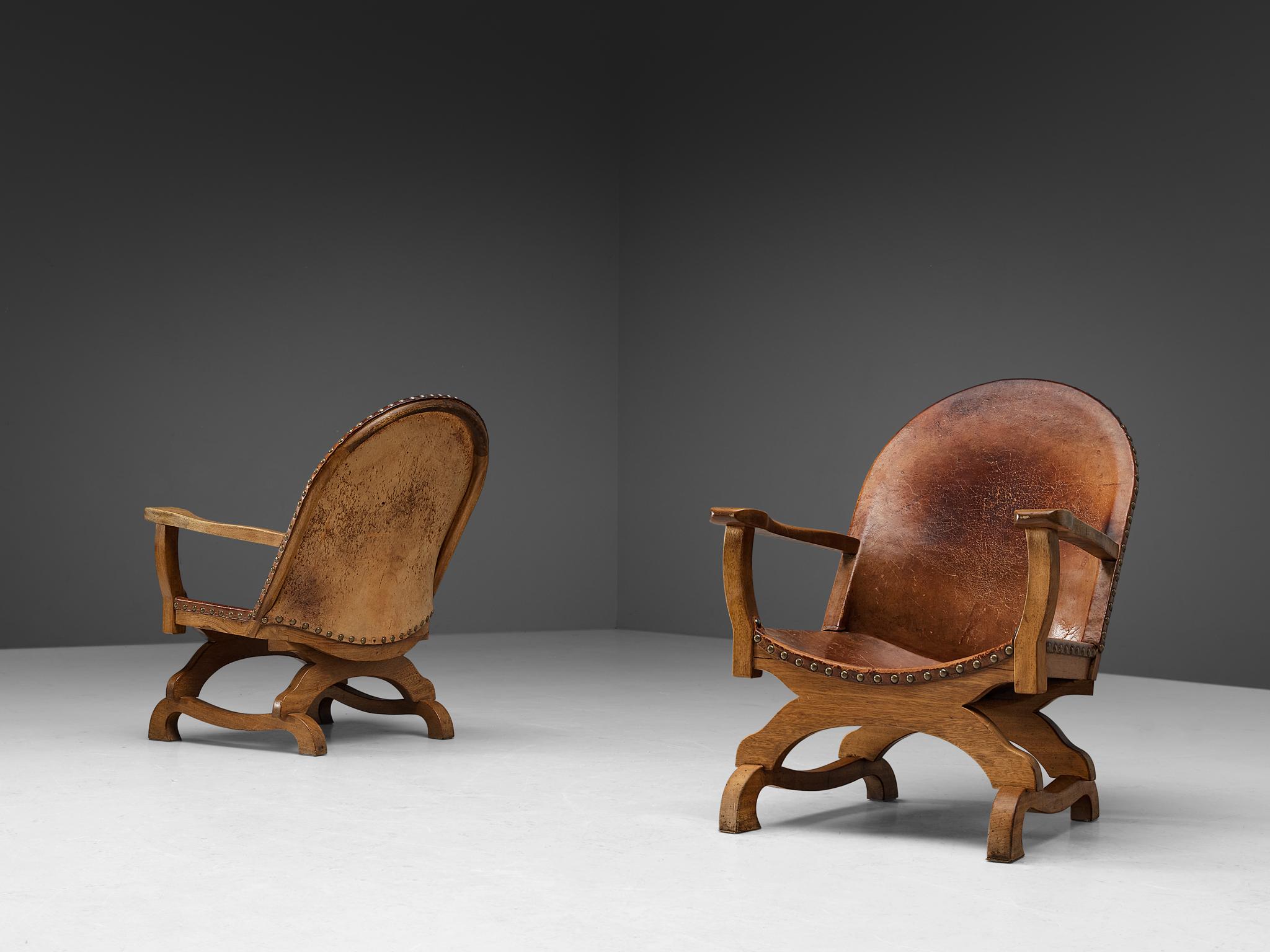 Pair of lounge chairs, leather, brass, oak, Spain, 1960s.

These lounge chairs originate from Spain and stylistically refer to the late 19th century Revival period. The construction of the base resembles the chair known in Spanish as 