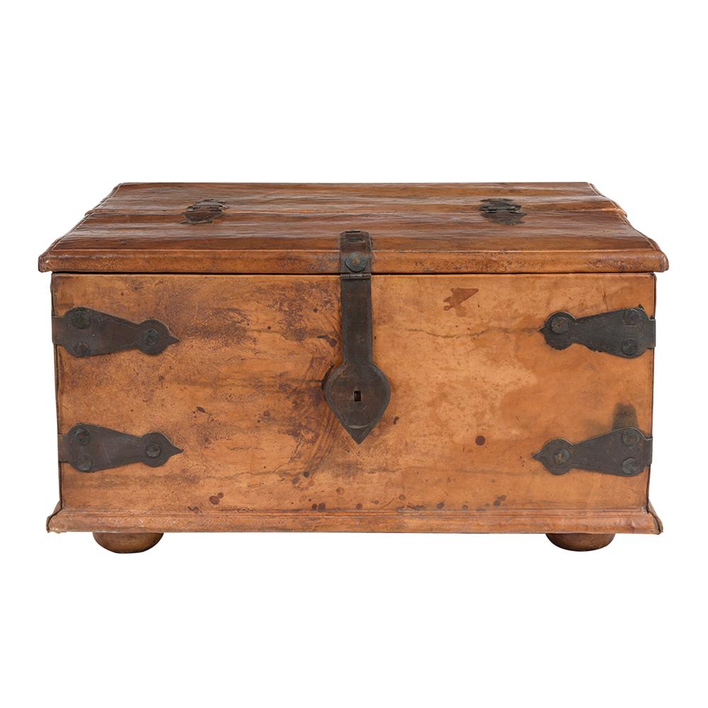 This Colonial-style parchment leather trunk is in good condition and features decorative iron/leather straps on the corners with two large iron handles on the sides. This trunk has two decorative hinges on the top, a big iron manual lock to close