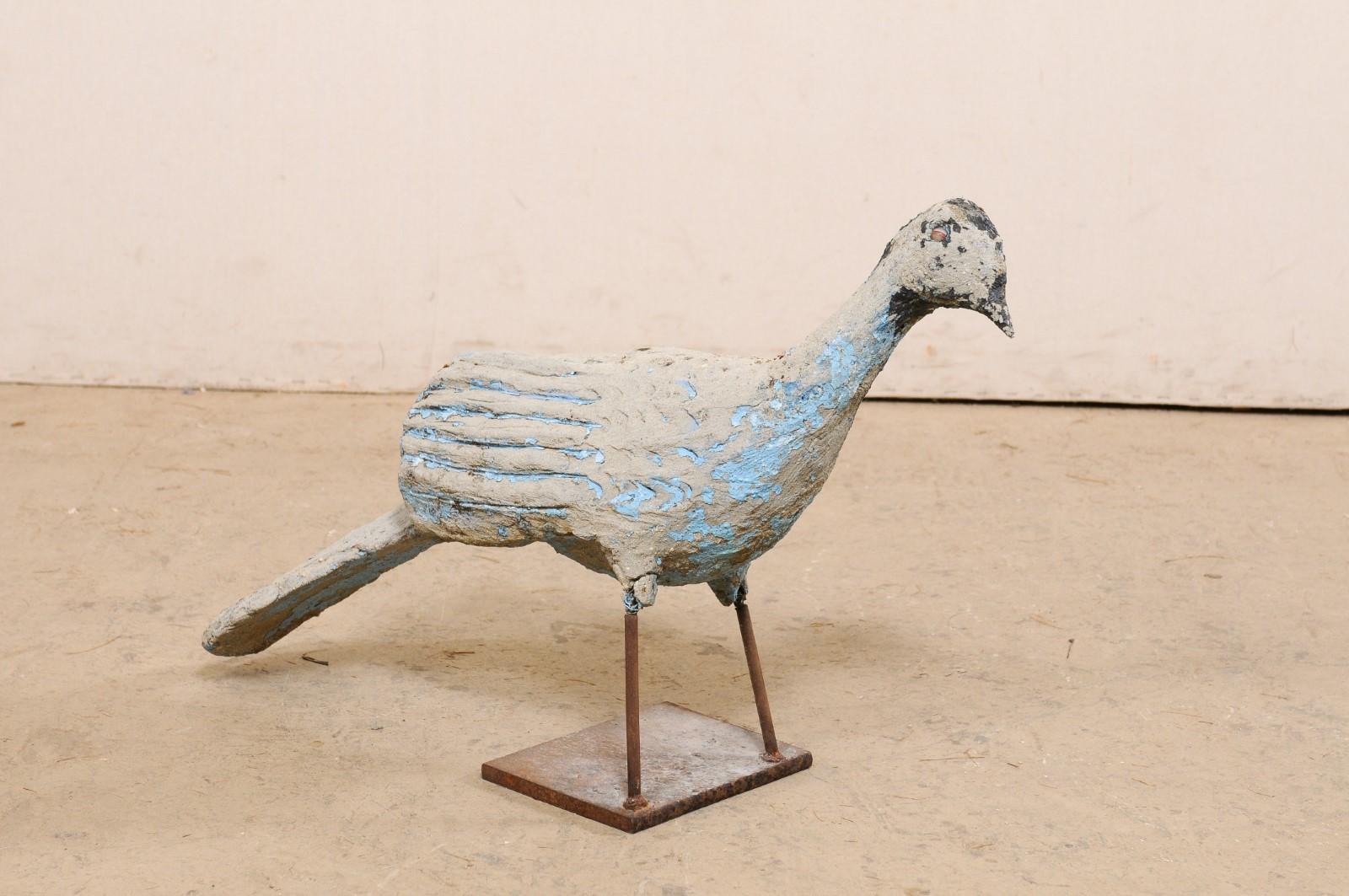 A Spanish painted peacock garden statue from the mid 20th century. This vintage statue from Spain, created of cast stone with iron legs, features a lovely little peafowl bird -standing upright with head slightly tilted in an inquisitive nature, and