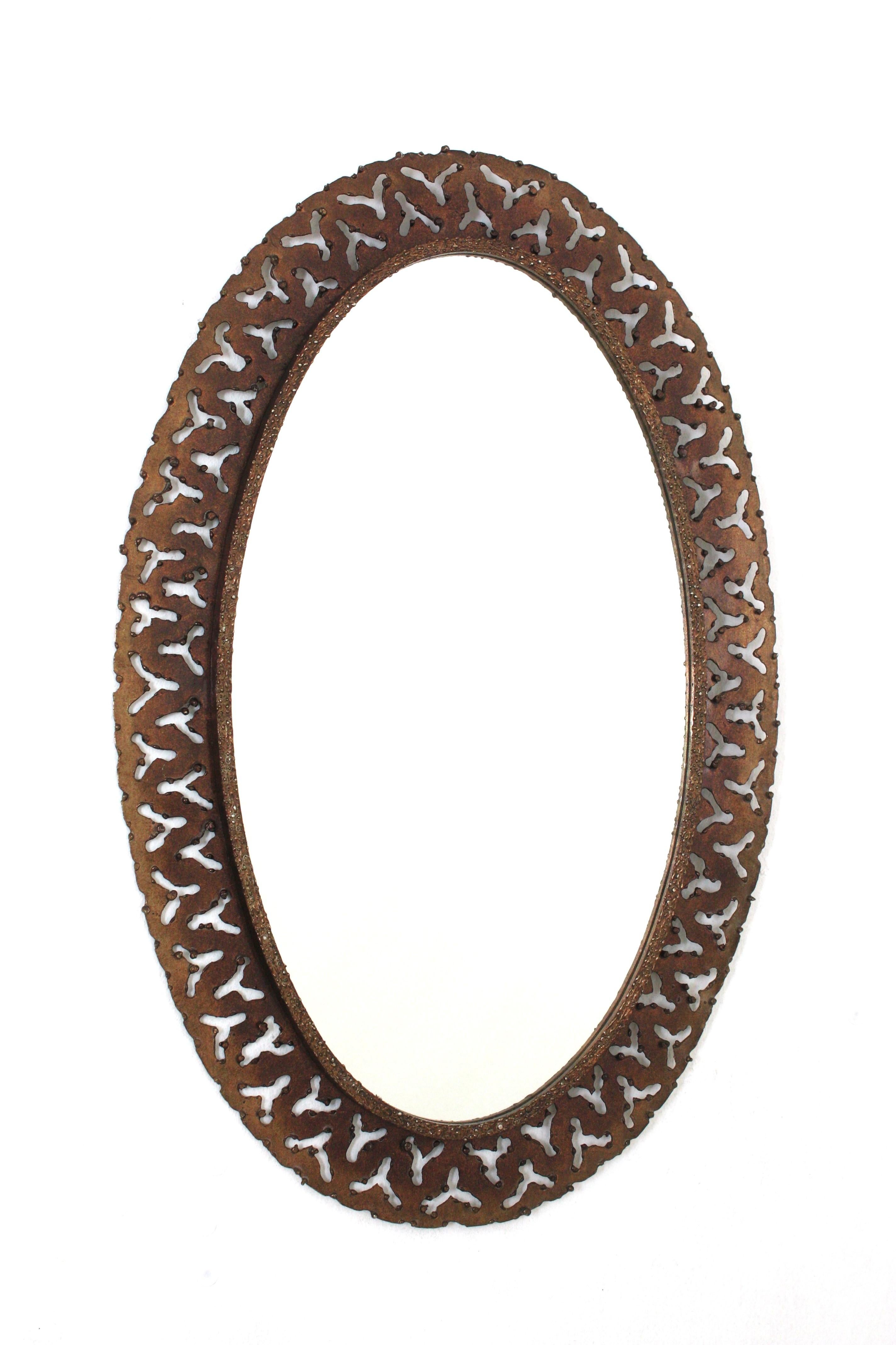 Miroir mural ovale avec cadre perforé, Espagne, années 1950
Miroir ovale en fer travaillé à la main avec motif perforé sur le cadre  et Brutalist Design.
Le cadre est fortement orné de perforations et d'accents en forme de gouttes de fer jusqu'au