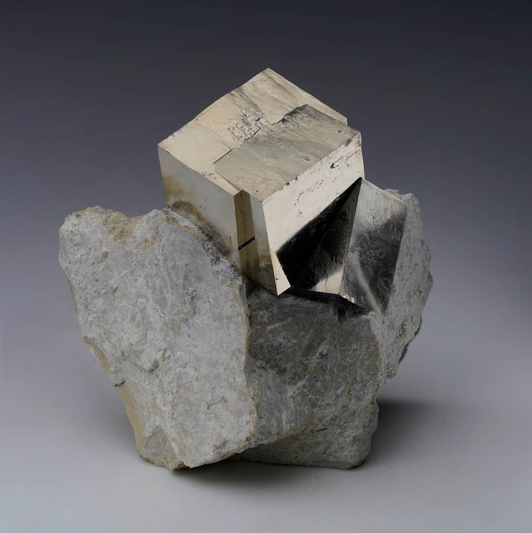 Este asombroso ejemplar de Navajún, España, presenta un gran cubo de Pirita de más de 2,5 cm de diámetro que crece a partir de otro cubo de Pirita de tamaño moderado con un color natural igualmente exquisito, un brillo especular y unas líneas y