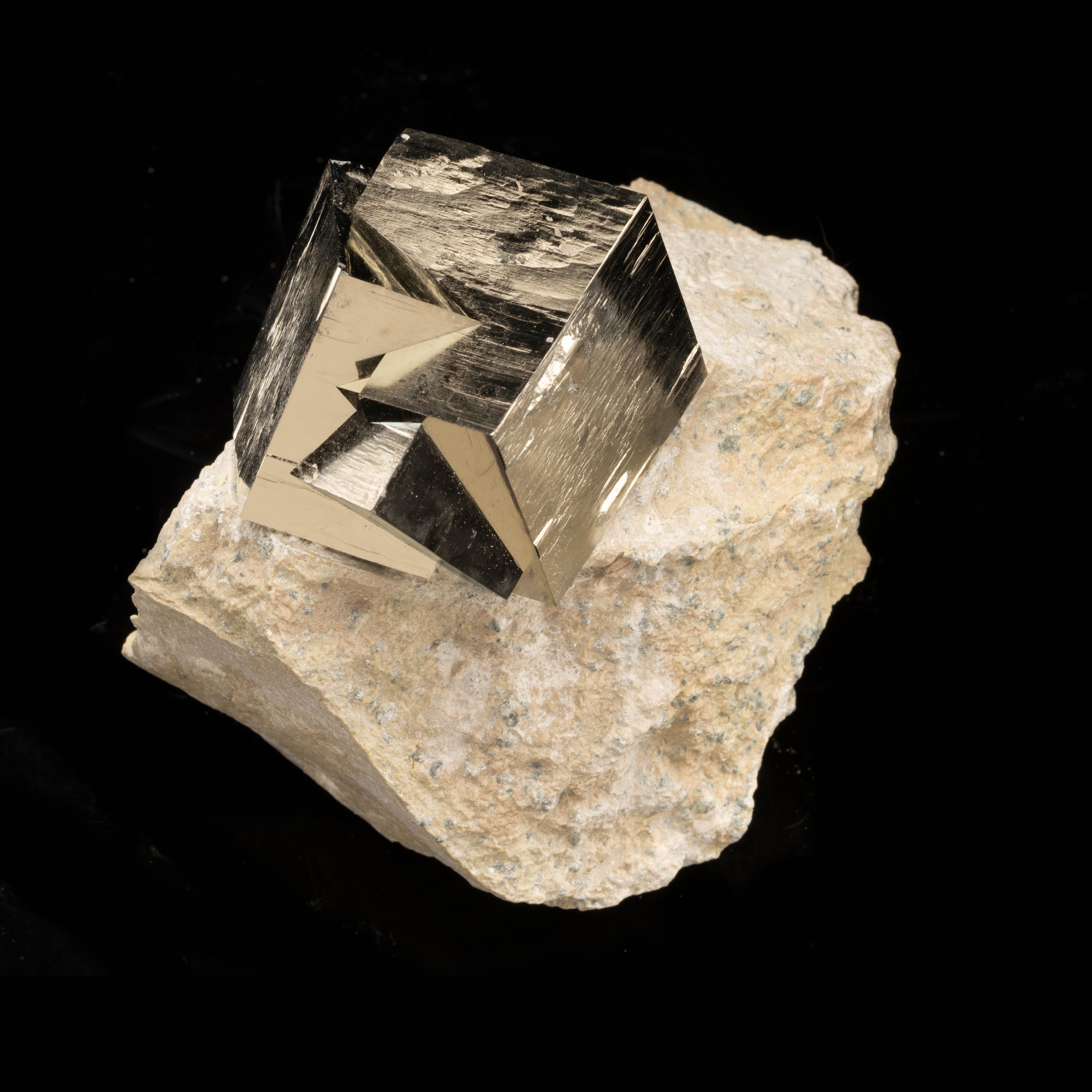 This singularly astonishing 2.10 pound specimen from Navajún, Spain features two large completely natural twinning pyrite cubes with a tertiary twin growing out of the cluster. This rare phenomenon grows out of a freestanding basalt matrix and