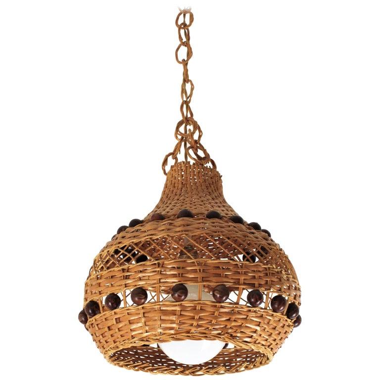 Spanish Mid-Century Modernist bell pendant lamp / lantern, woven wicker, rattan, 1960s
This eye-catching suspension lamp features a handwoven wicker and rattan bell shaped shade with two lines of brown balls. It hangs from a chain with round rattan
