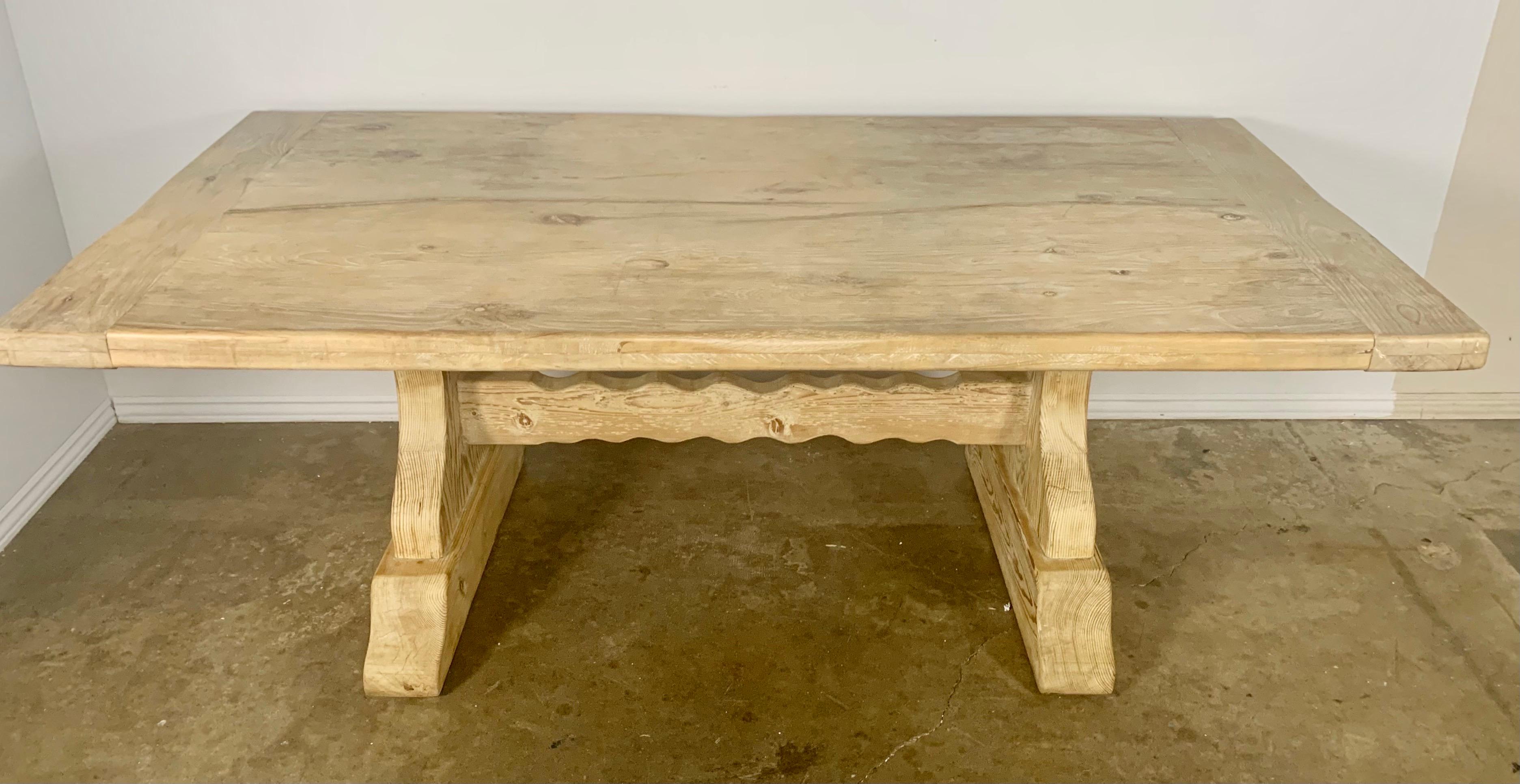 Bleached Spanish style pine dining table. Two pedestals hold up the large rectangular top. The pedestals are connected by a center stretcher. The table is sturdy and has a beautiful worn bleached finish.