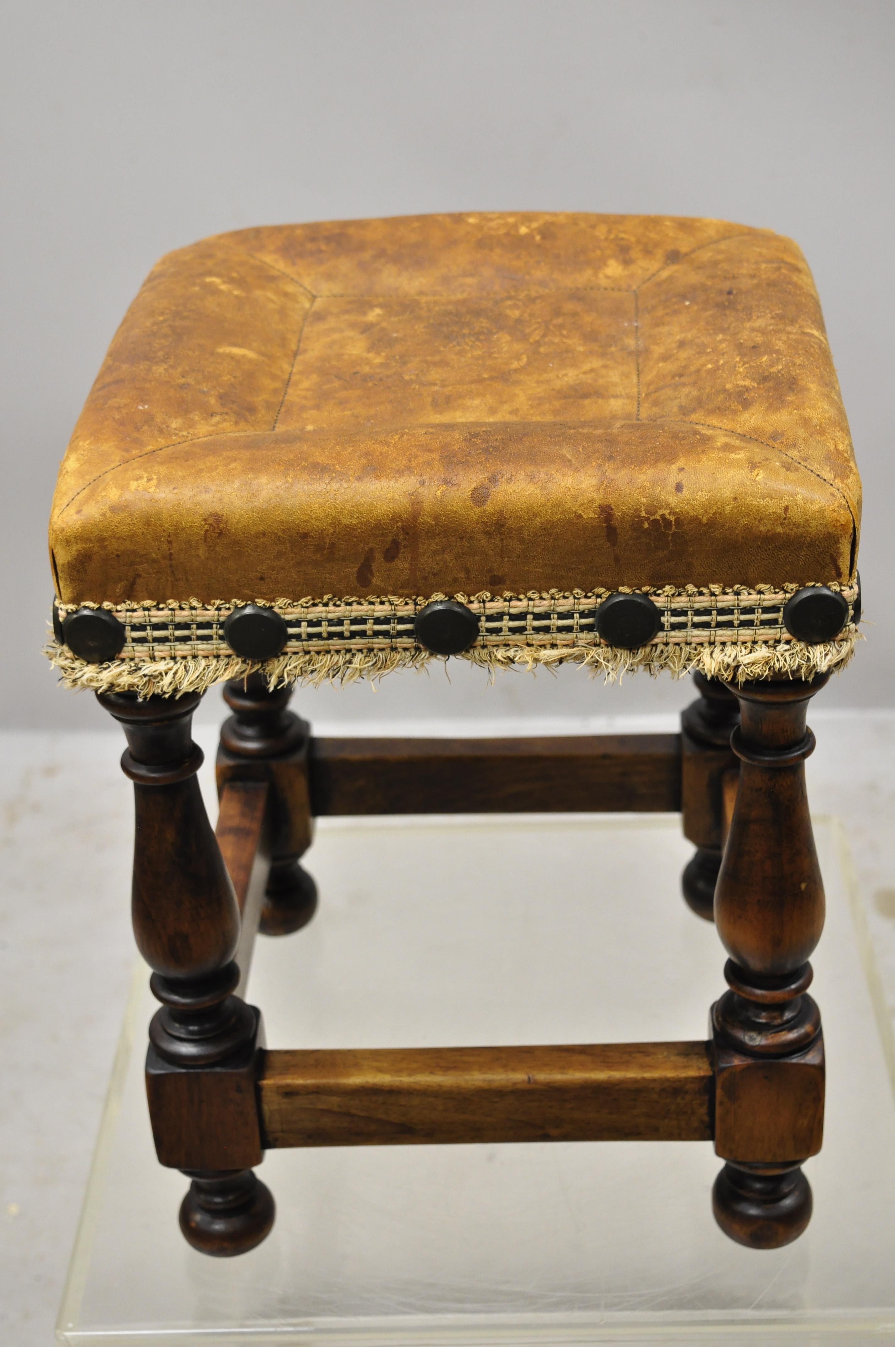 Spanish Renaissance brown distressed leather walnut turn carved legs footstool. Item features turn carved legs, brown distressed leather seat, nailhead trim, solid wood construction, beautiful wood grain, quality craftsmanship, great style and form,