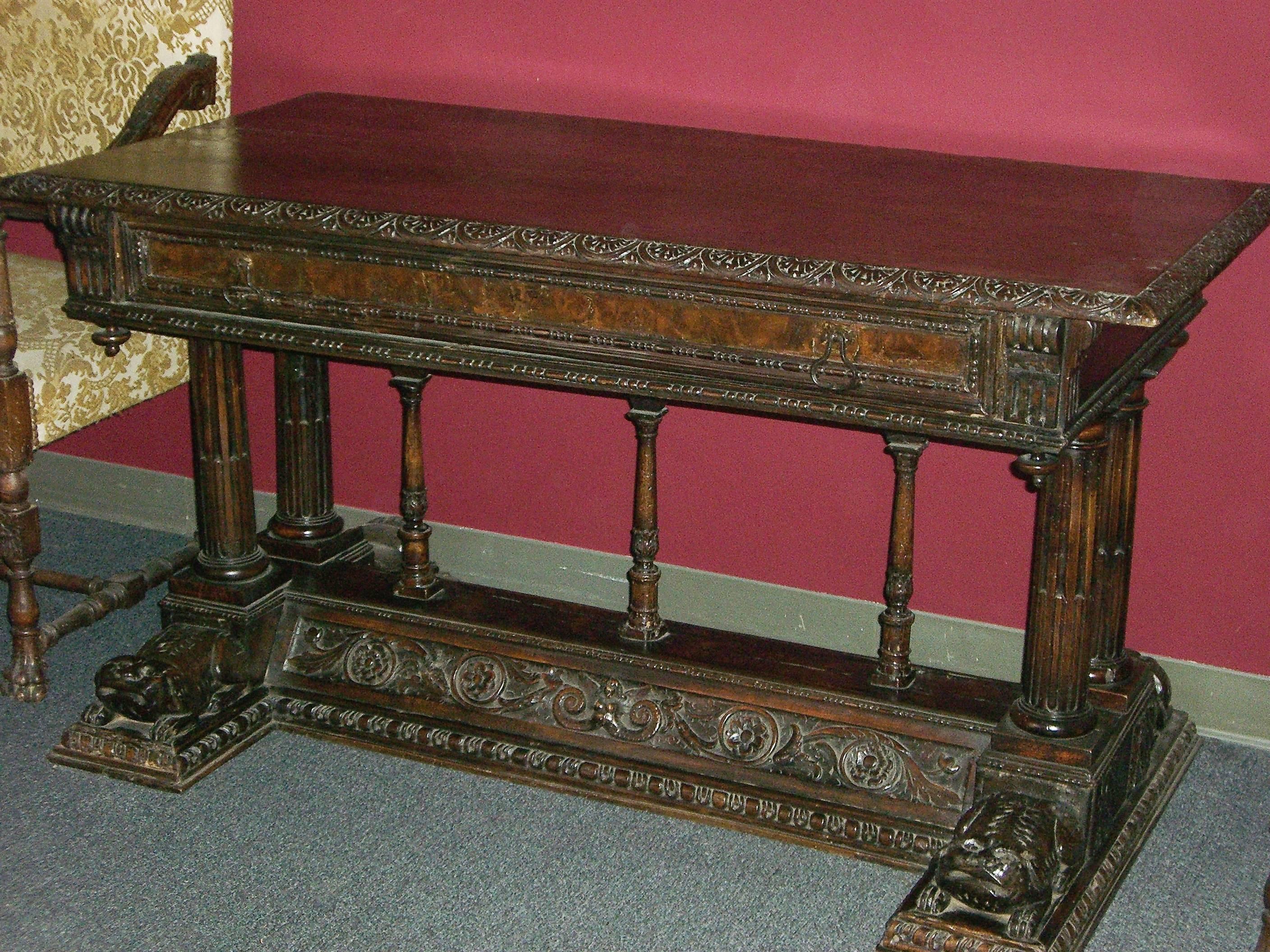Spanish Renaissance hand-carved walnut table, 16th century and later. The solid walnut top with carved trimmed edges over a frieze containing one large drawer with two bronze handles resting on four fluted columns and three small center supports,