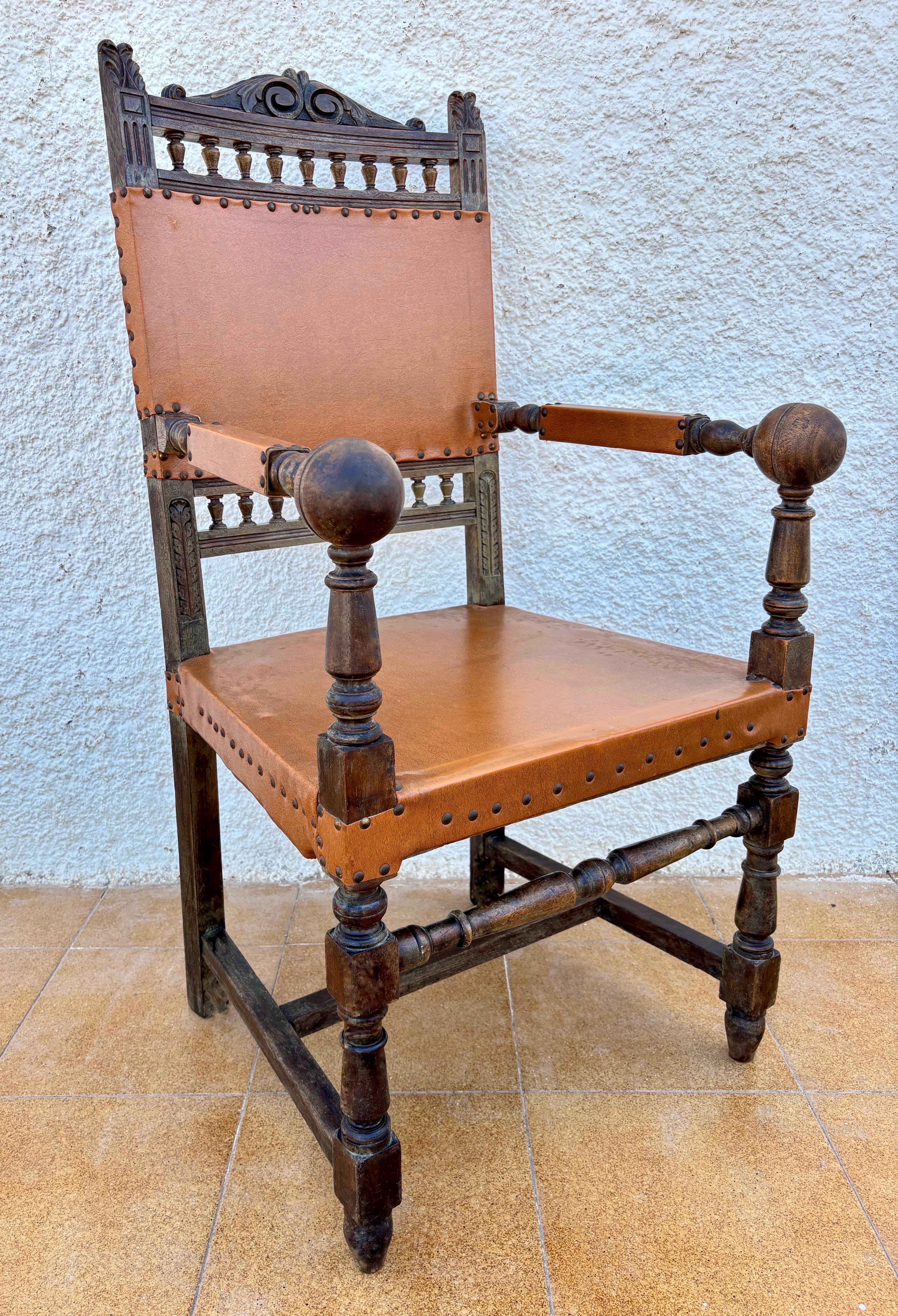 Spanischer Renaissance-Revival-Sessel aus Eichenholz mit originaler Sitzfläche und Rückenlehne aus Leder, aus dem frühen 20.
Das Stück verfügt über gedrechselte Beine und Armlehnen, eine dekorative geschnitzte Kammleiste und Lederverkleidungen, die
