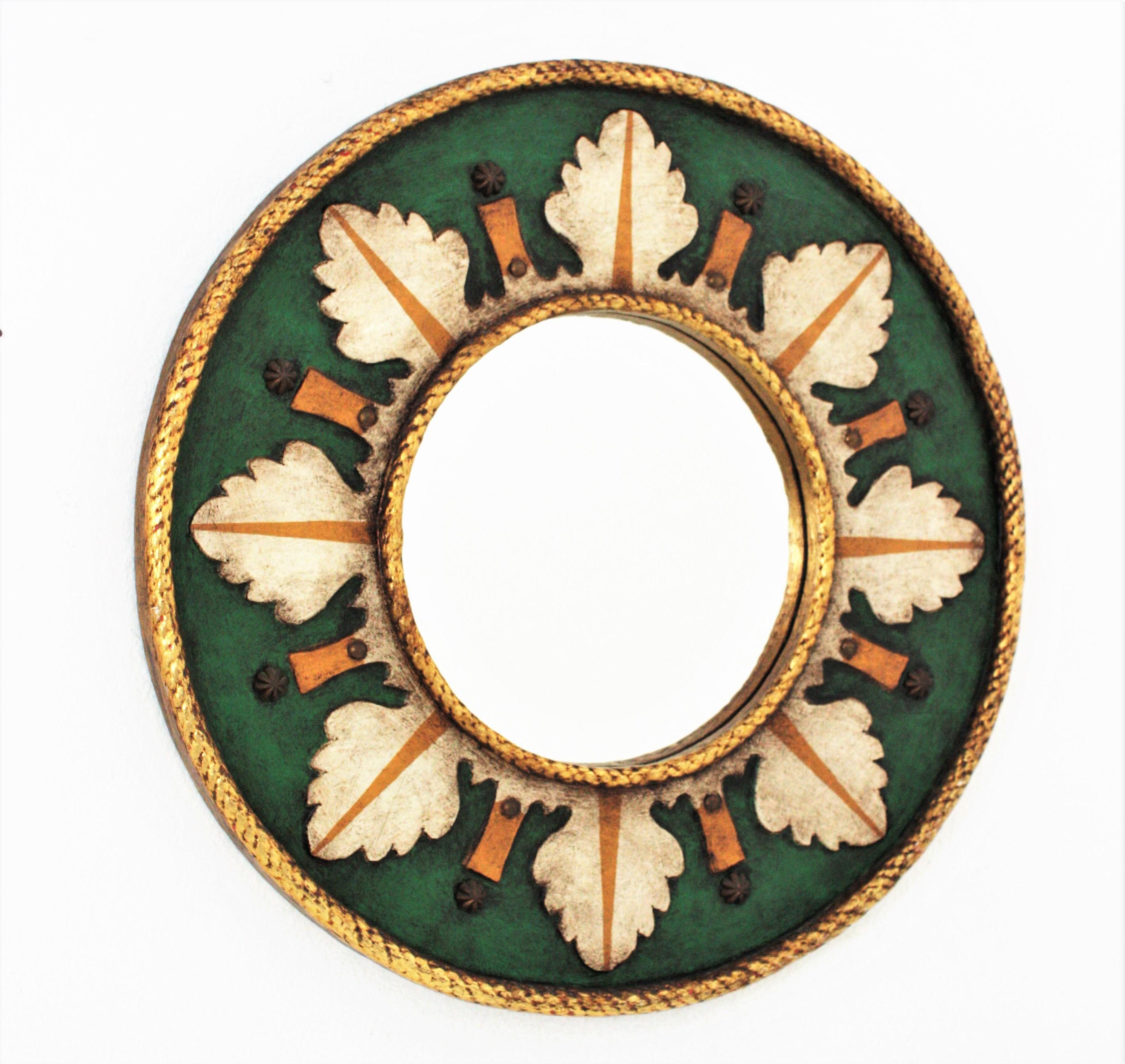 Eye-catching polychrome sunburst mirror Renaissance Inspired, Spain, 1960s.
Beautiful round mirror with nice foliage decorations in sunburst disposition in green, beige and orange colors. A gold leaf  gilded rim surround the glass and the frame at