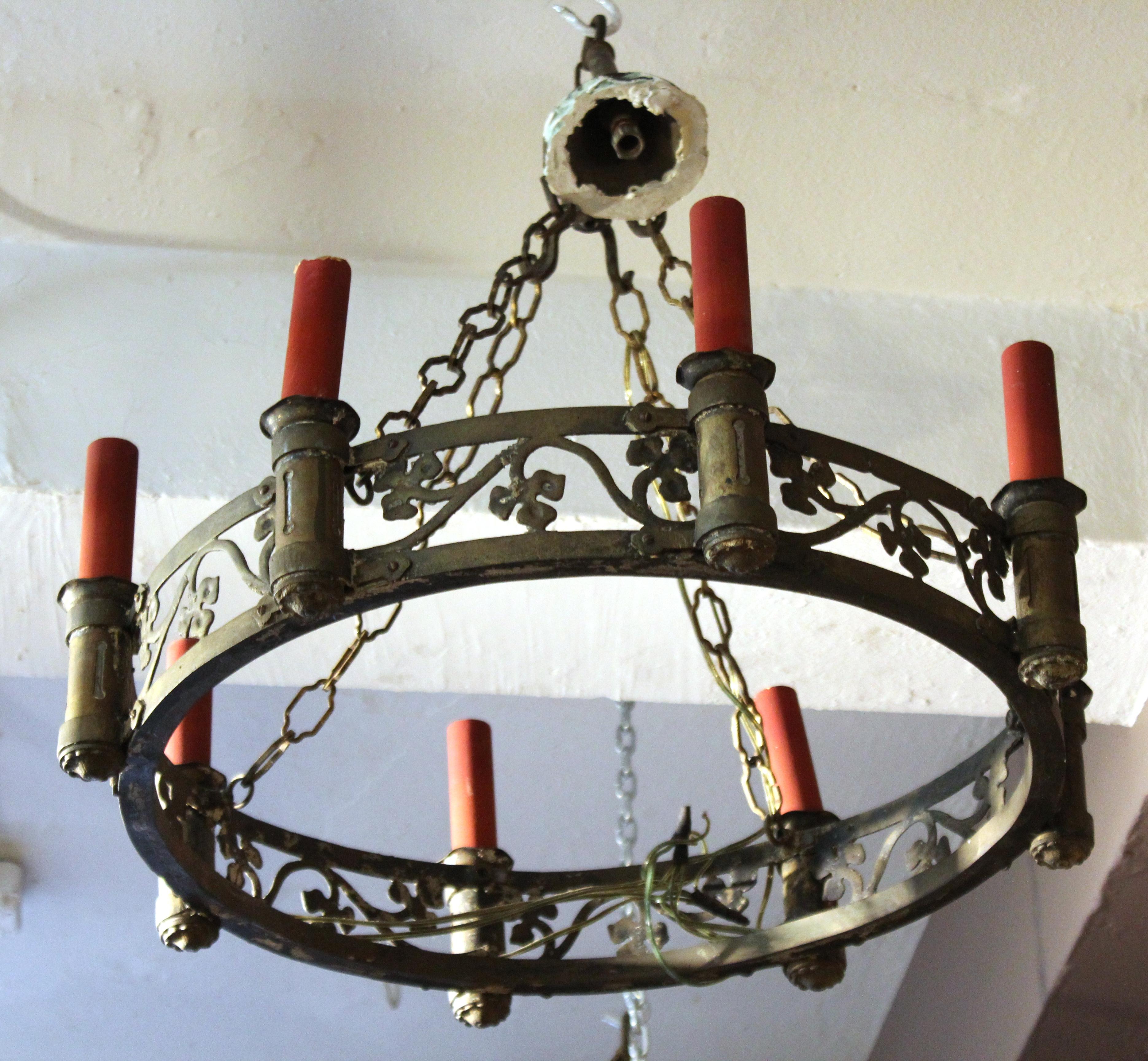 Continental Spanish Renaissance Revival or Neo-Gothic style pair of wrought gilt brass eight-light chandeliers with foliage designs and red cardboard faux candle sleeves. The pair has wrought link chains with four-hook ceiling caps. In good antique