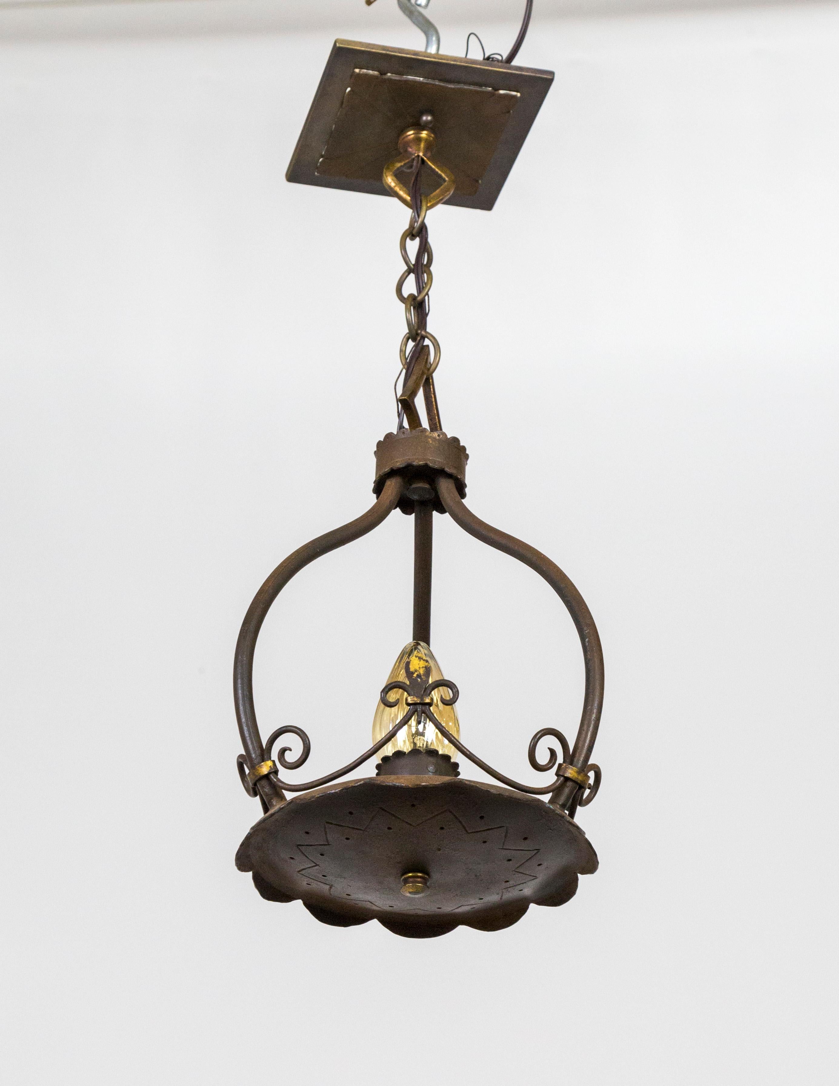 A small, wrought iron pendant; with one upward facing socket with three curved arms hung with chain to a square canopy. With decorative details, wire fluer de lis, scalloped plate base, and unusual hardware. 1920s. Newly rewired. 20.25