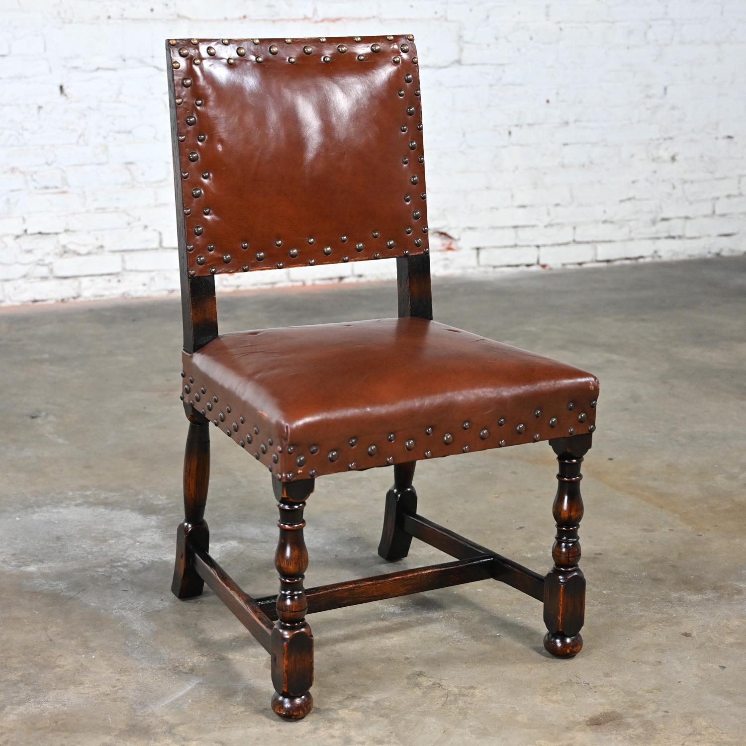 Marvelous vintage Spanish Revival Century Furniture side chair comprised of a dark stained oak frame, & cognac leather seat & back with antiqued brass nail head trim details. Beautiful condition, keeping in mind that this is vintage and not new so