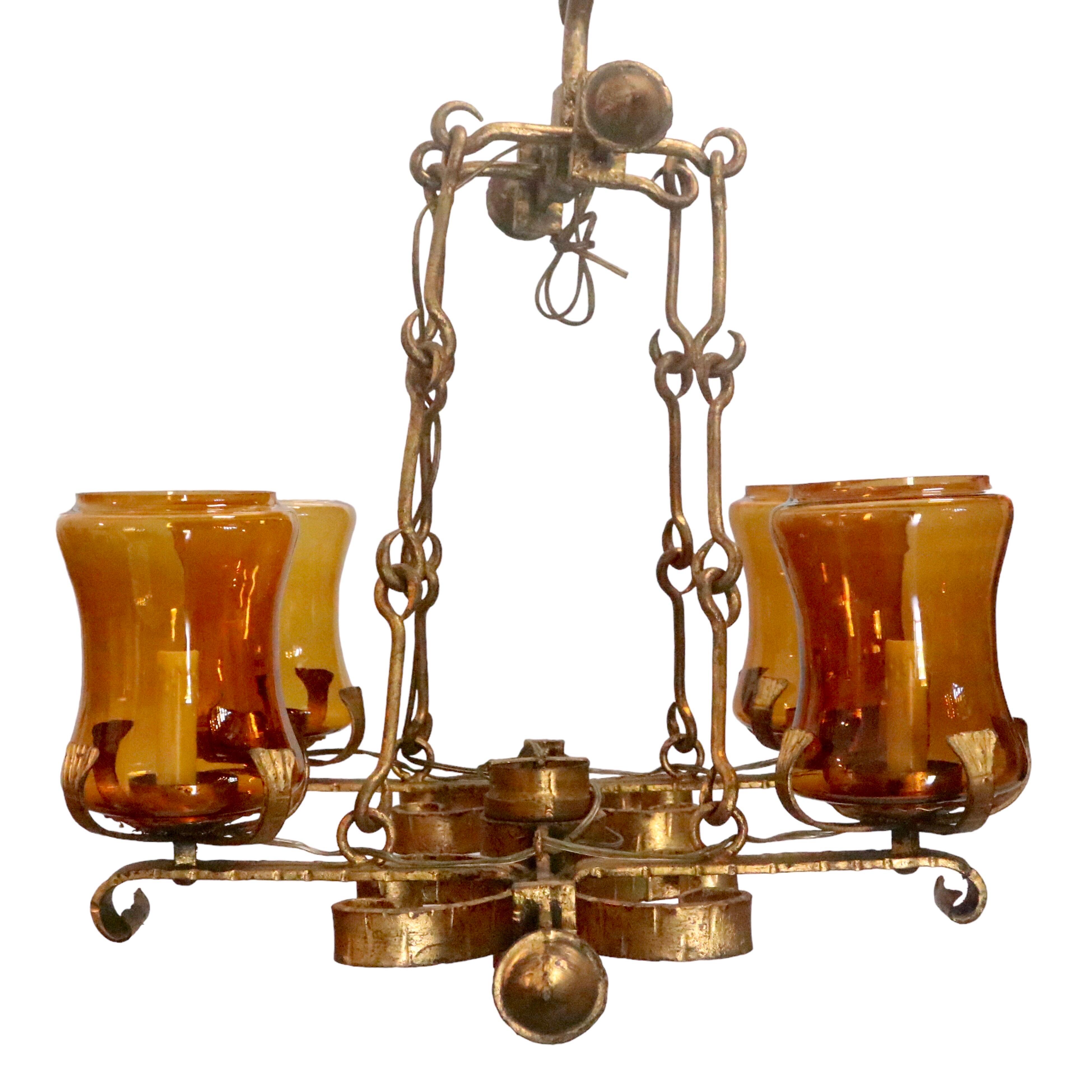Hand forged wrought Spanish Revival Chandelier.  Elongated shape. Perfect for entryway, living room, kitchen island and dining rooms. 

Features an antique gold finish with gold colored glass hurricane shades.

Fixture Dimensions: 23” Height x 30”