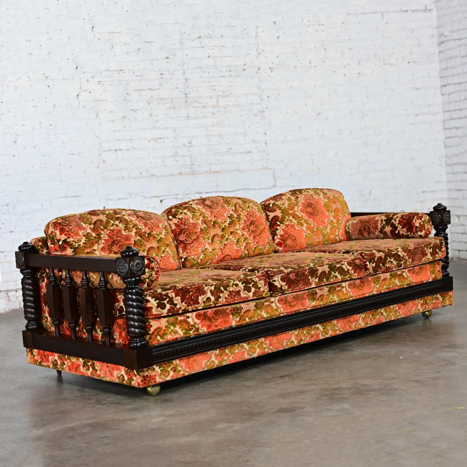 Incredibile divano vintage in ciniglia con arazzo floreale in stile Revival spagnolo o mediterraneo composto da una struttura in legno scuro con fianchi a fuso d'orzo, dettagli decorativi in ottone, tre cuscini di seduta in schiuma imbottiti e