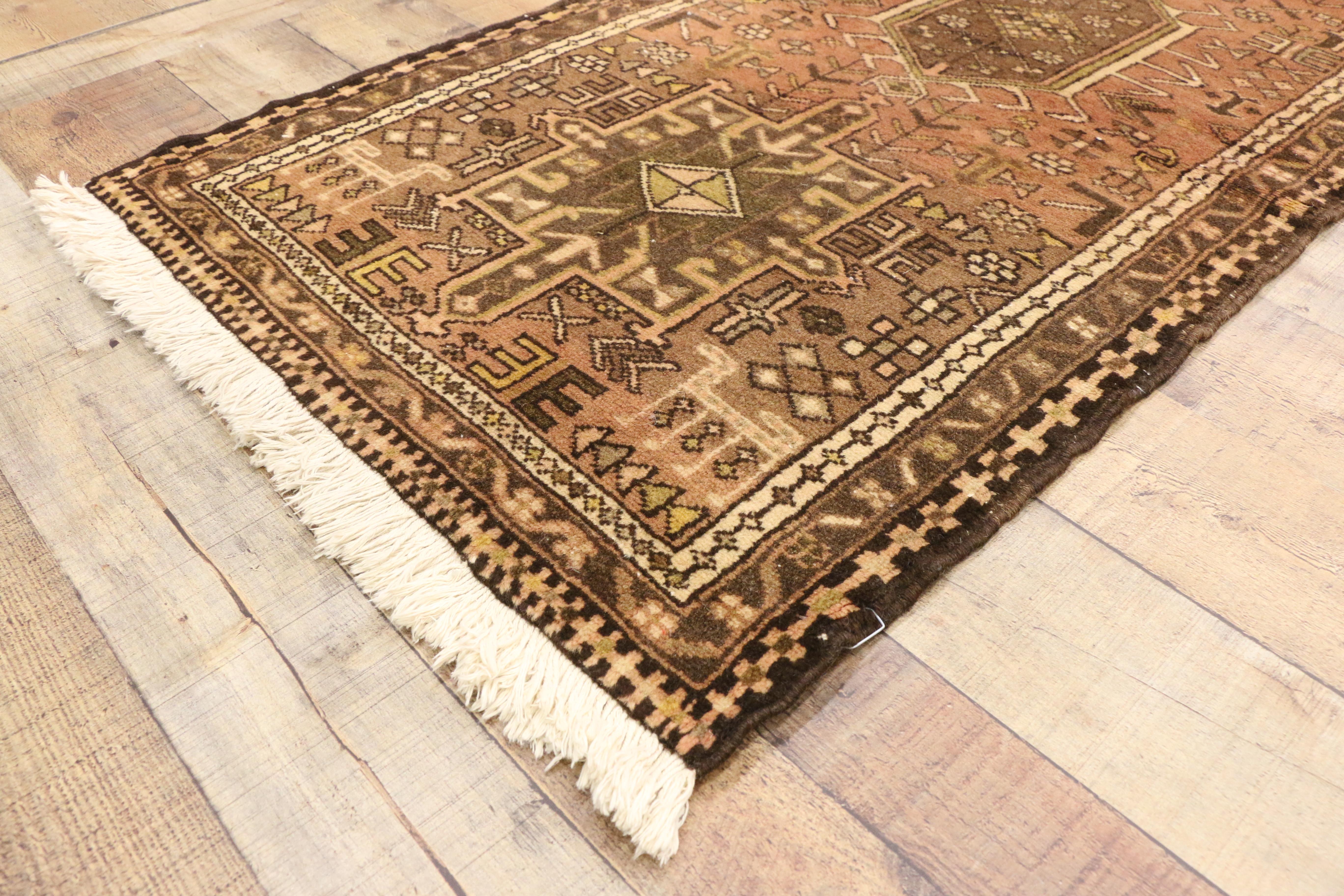 73679, Spanish Revival Style Vintage Persian Heriz Runner, Narrow Hallway Runner. This hand-knotted wool vintage Persian Heriz runner features a series of square and hooked amulet medallions surrounded by an array of tribal motifs. Earthy hues of
