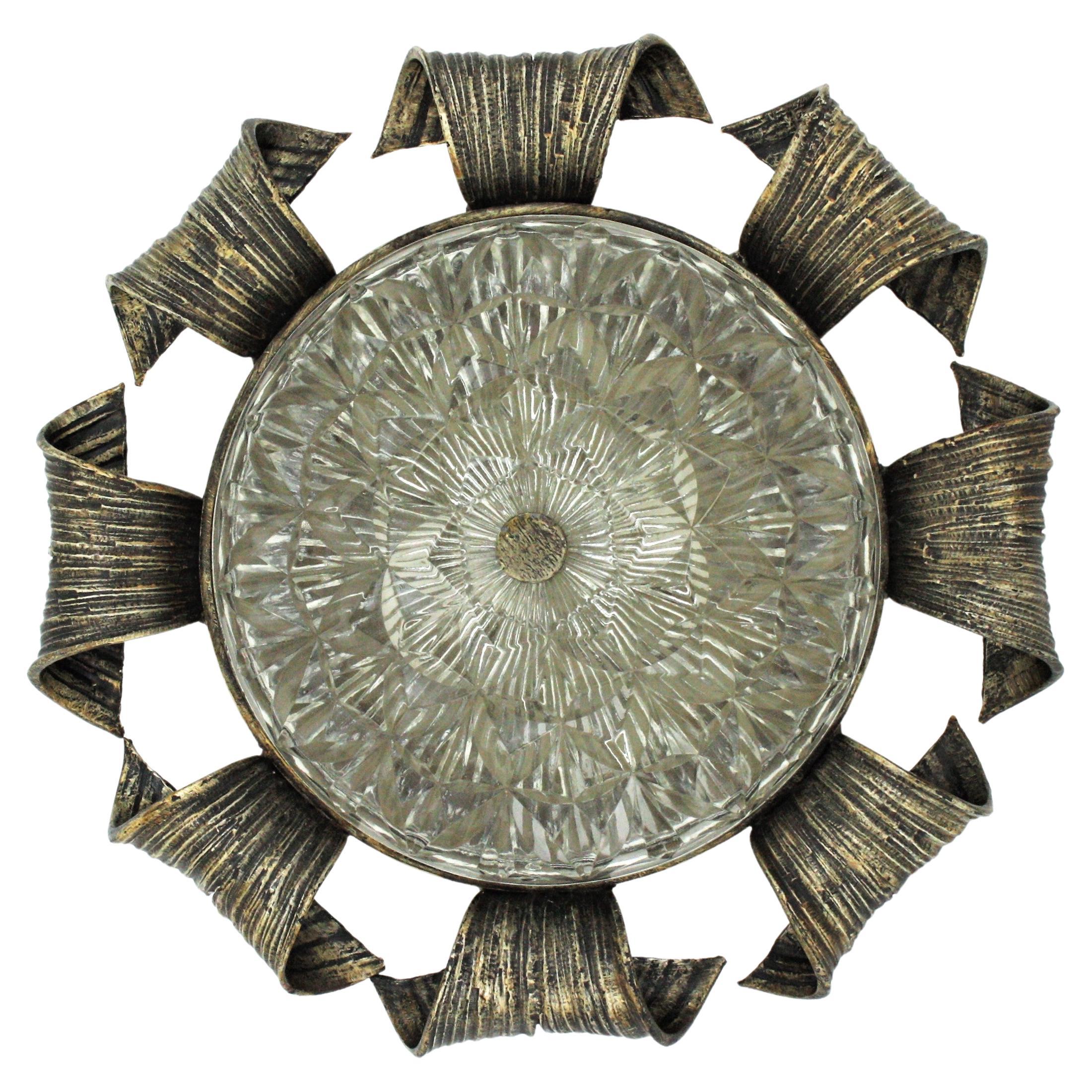 Handsome wrought iron sunburst flush mount / wall light with scrolled frame and pressed glass shade, Spain, 1940s-1950s.
This hand forged flush mount has an interesting design and a very heavy construction. The frame has thick scrollwork accents