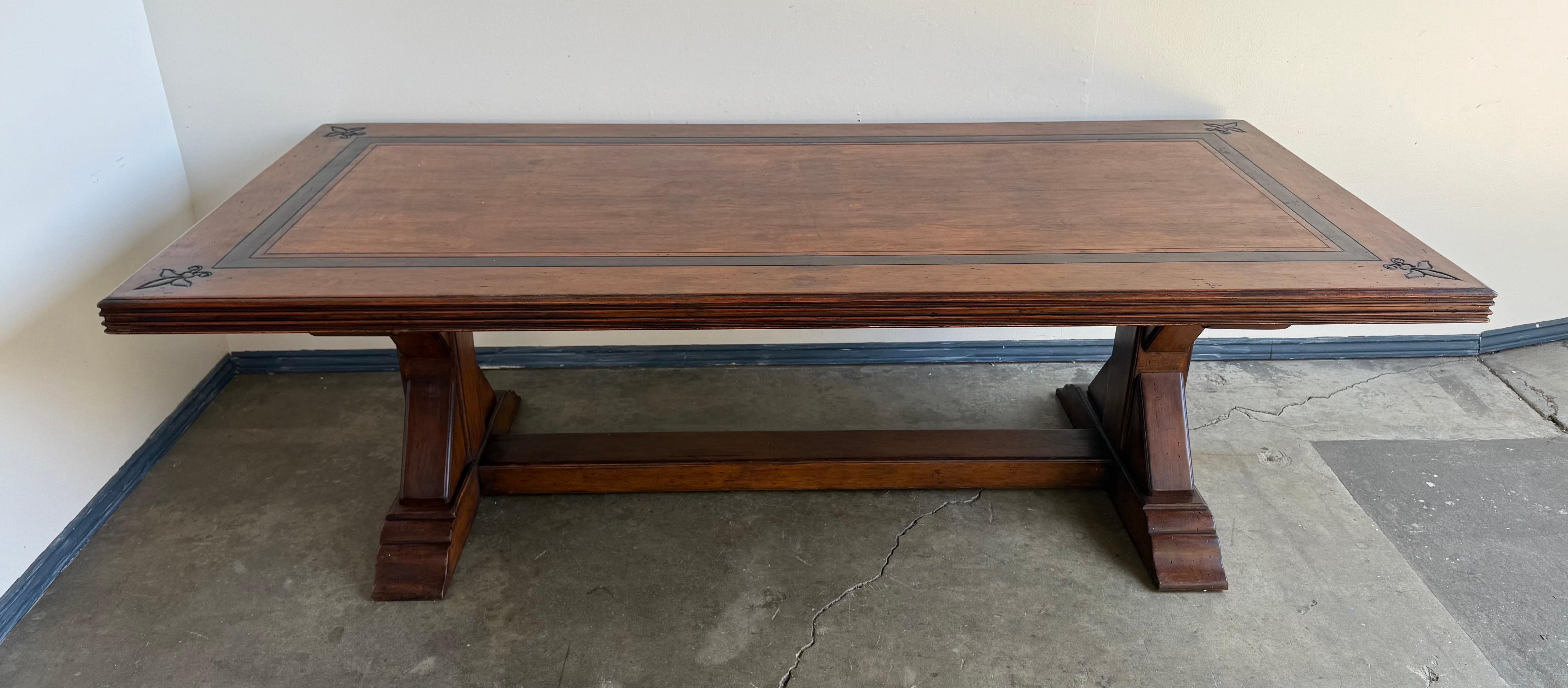 Ein eleganter Esstisch aus Nussbaum im spanischen Revival-Stil aus dem frühen 20. Jahrhundert, der sich durch raffinierte Handwerkskunst und schlichte architektonische Linien auszeichnet. Die rechteckige Platte hat eine eingelegte Umrandung mit
