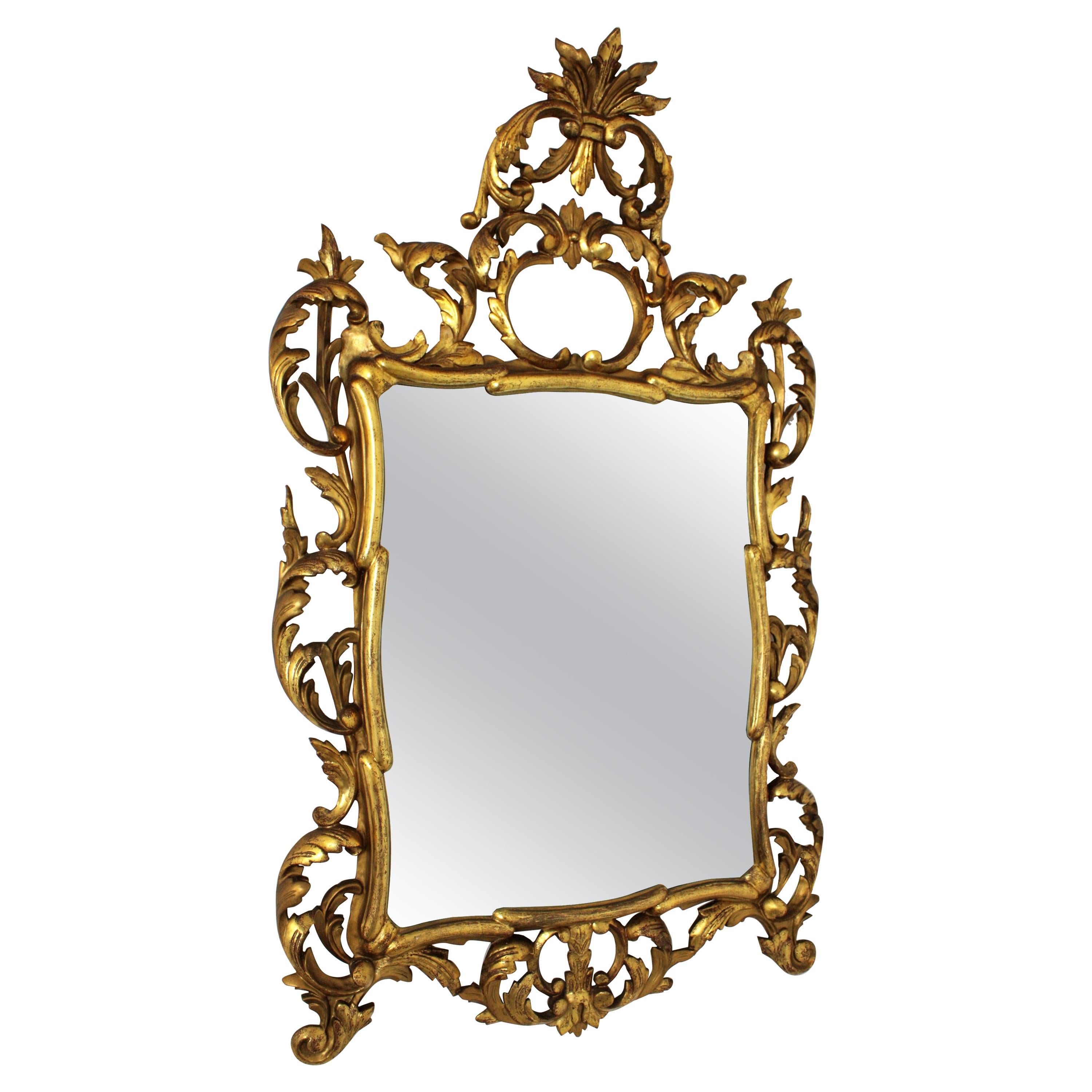 Spanish rococo style finely carved gold leaf giltwood mirror.
A highly decorative finely carved Rococo style mirror with gold leaf finish and beautiful original patina. Frame with details of scrolled acanthus leaves and an important carved crest.