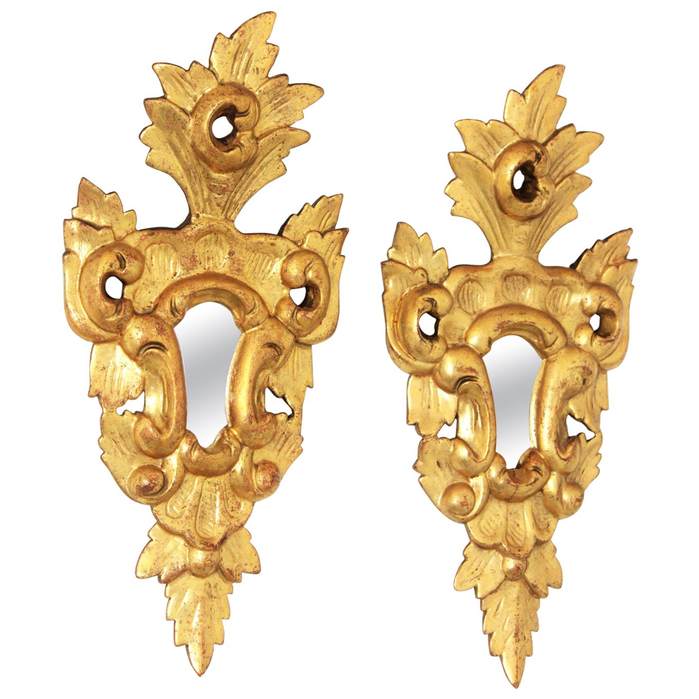 Exquisite Rococo style pair of small scale carved mirrors with a crest on the top and carved naturalistic details at the frames.
These pieces are unusual due to their size, they wear their original glasses and they are made of carved wood, gesso and