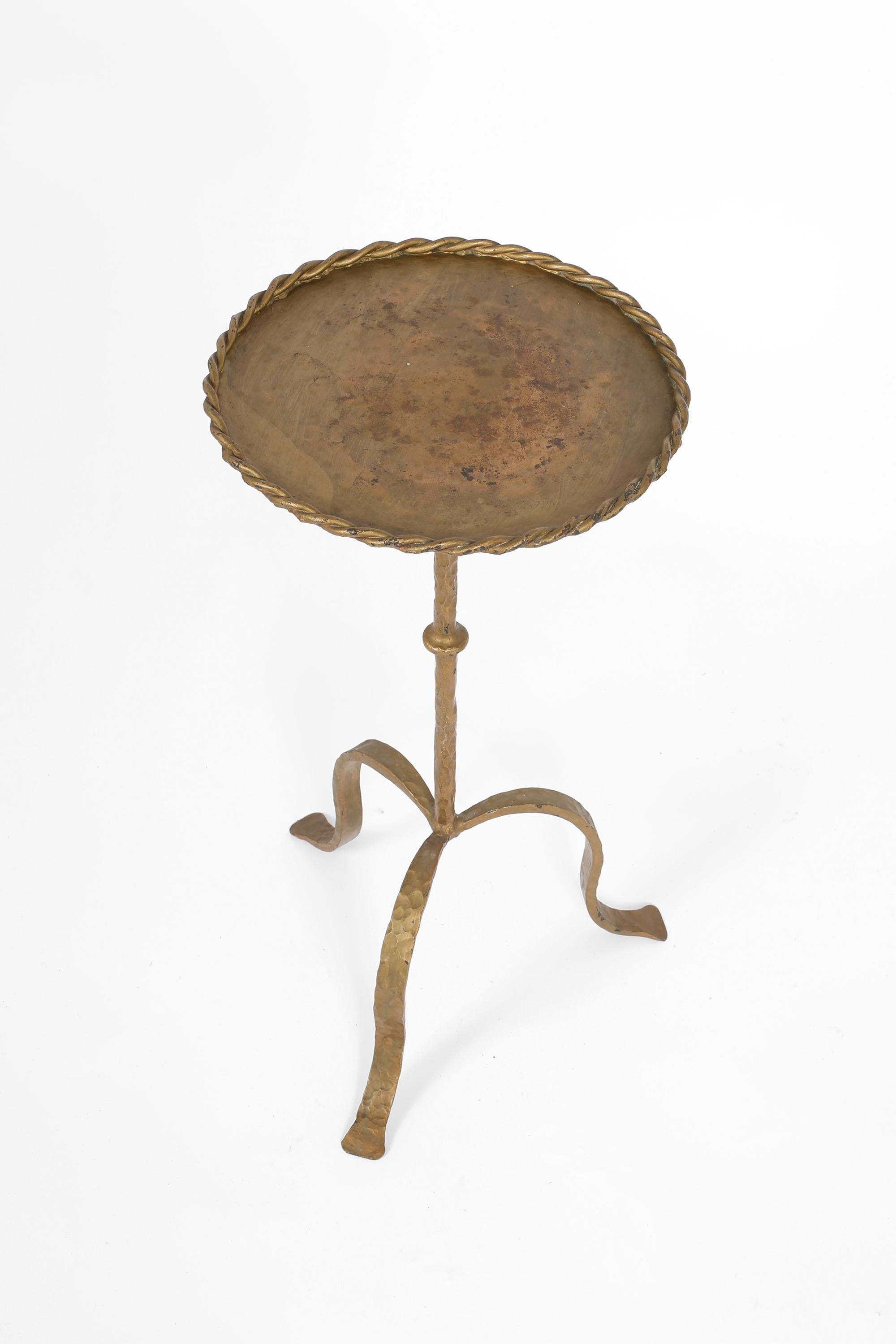 A gilt forged iron Martini table, with twisted ‘rope’ edge, beaten stem and tripod base. Spanish, c. 1950s.