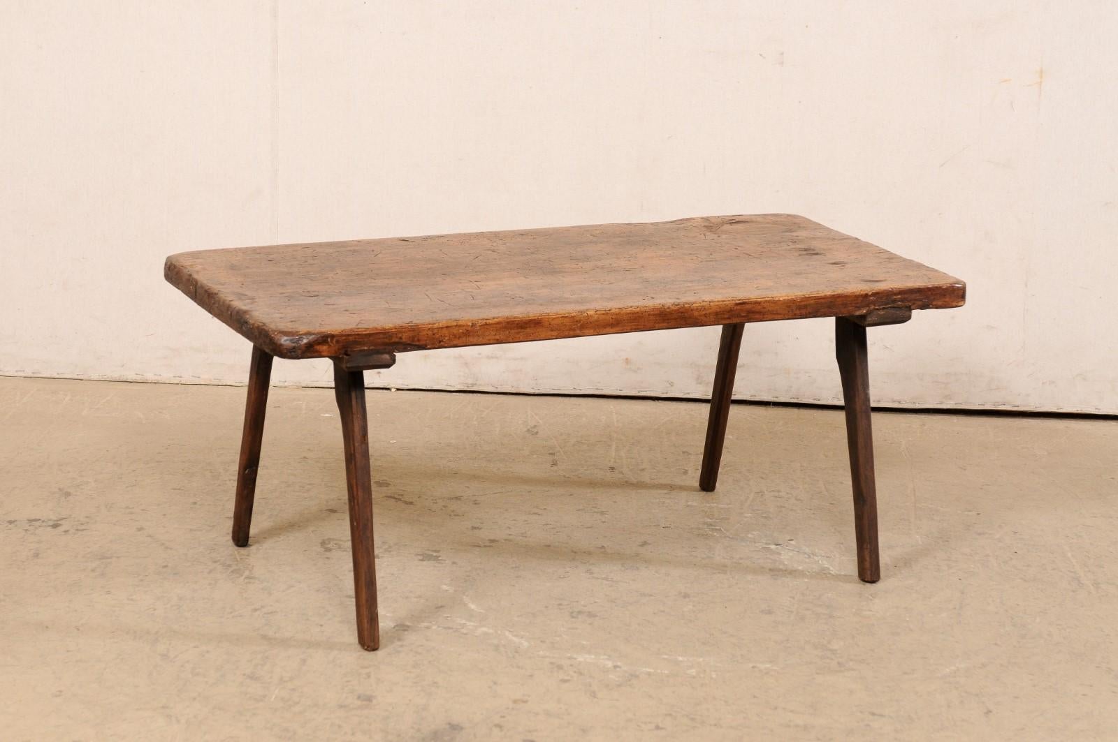A Spanish single-board top wooden coffee table from the 19th century. This antique table from Spain features a single board wood top, rectangular in shape with smoothed edges. It is raised on four legs which cant in outwardly fashion. The wood has a