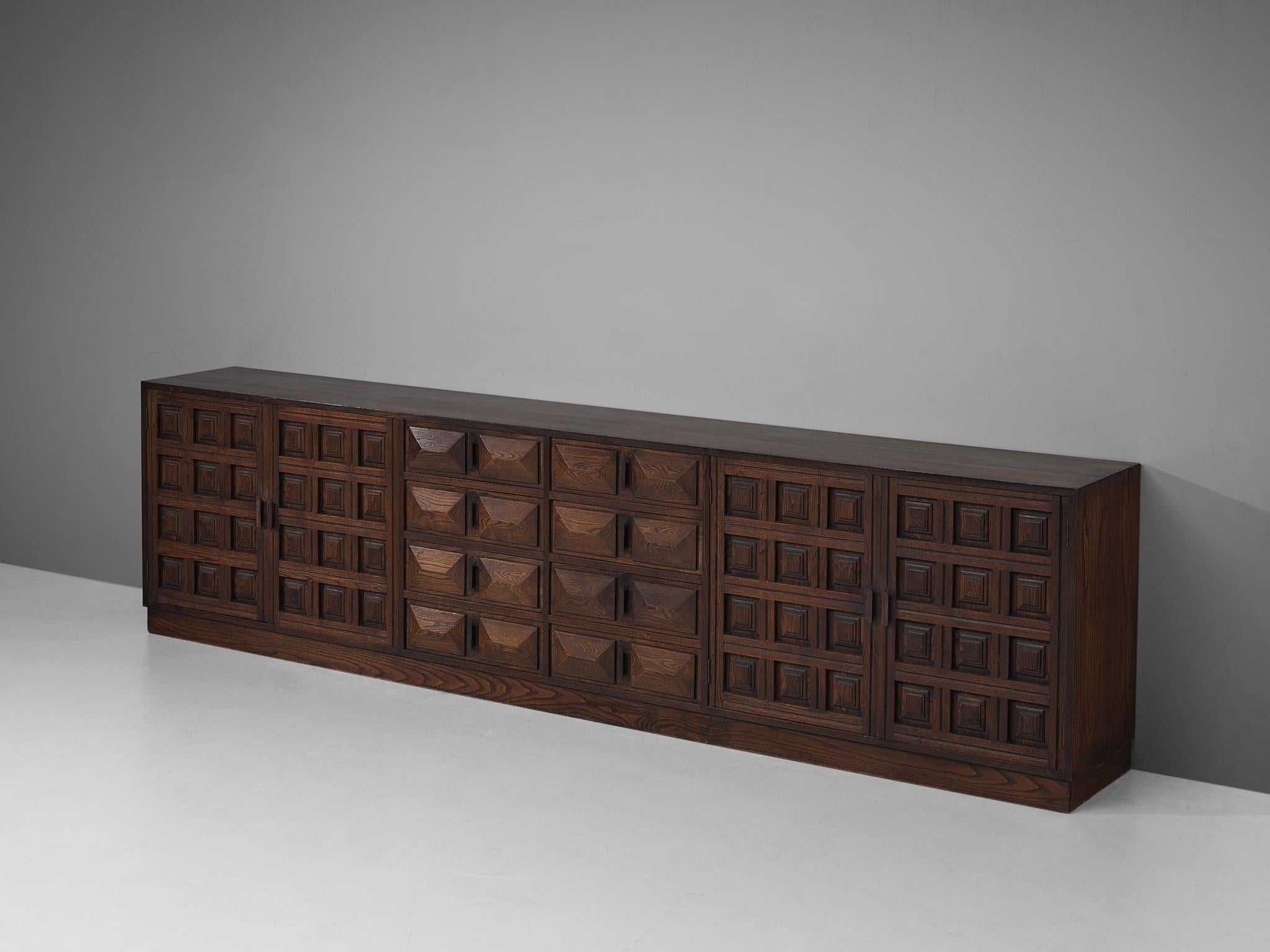 Sideboard, oak, Spain, 1960s. 

Outstanding Spanish sideboard that is executed in beautiful dark stained oak. The four-door credenza features doors with a graphic carved pattern. Note the exquisite woodwork on the frontpanels of the eight drawers