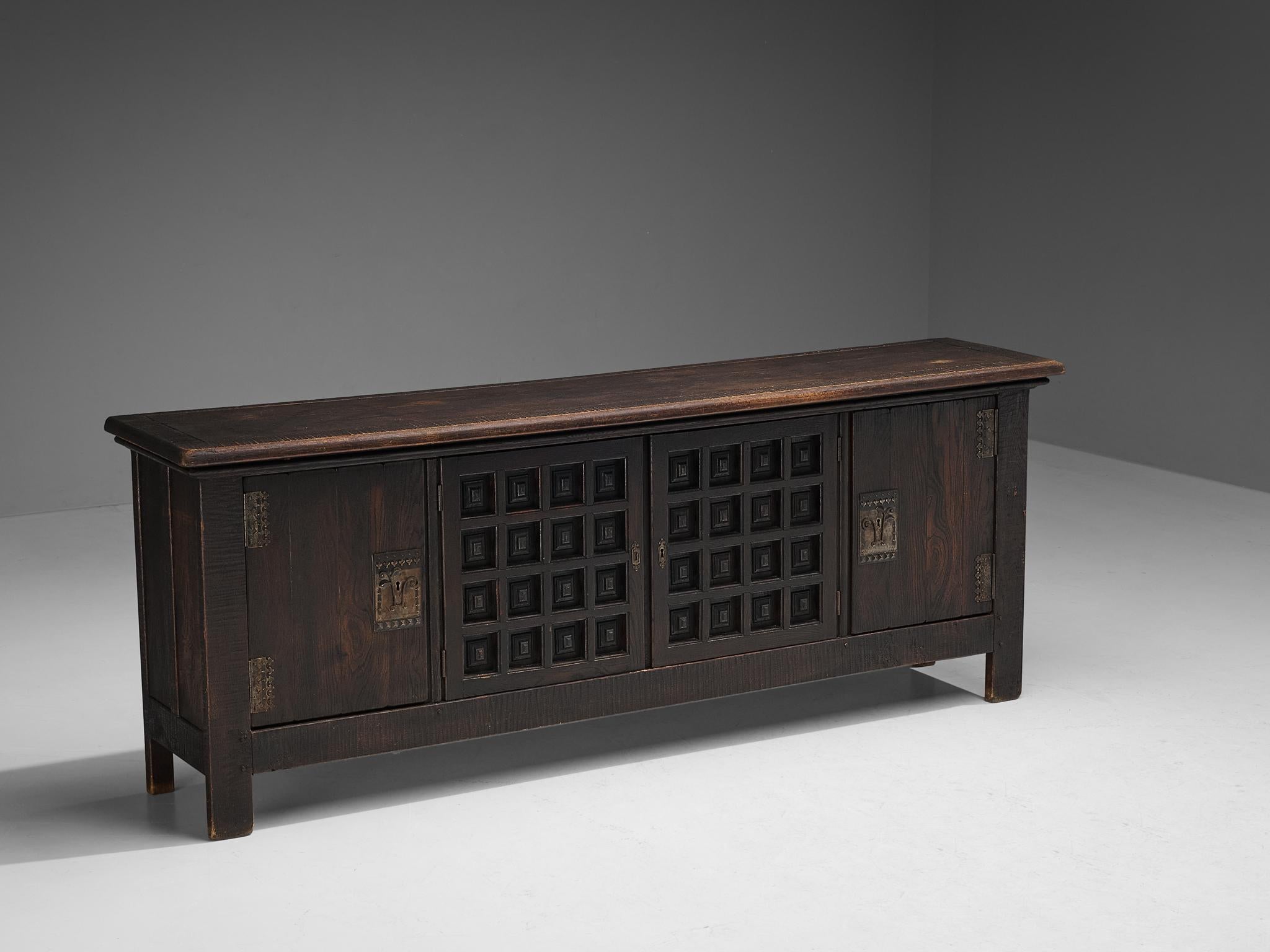 Sideboard, stained oak, metal, Spain, 1940s

This grand Spanish Revival inspired sideboard embodies a solid construction where clear lines and sturdy shapes are allowed to emerge in the design. Thanks to its rectangular shape, the credenza