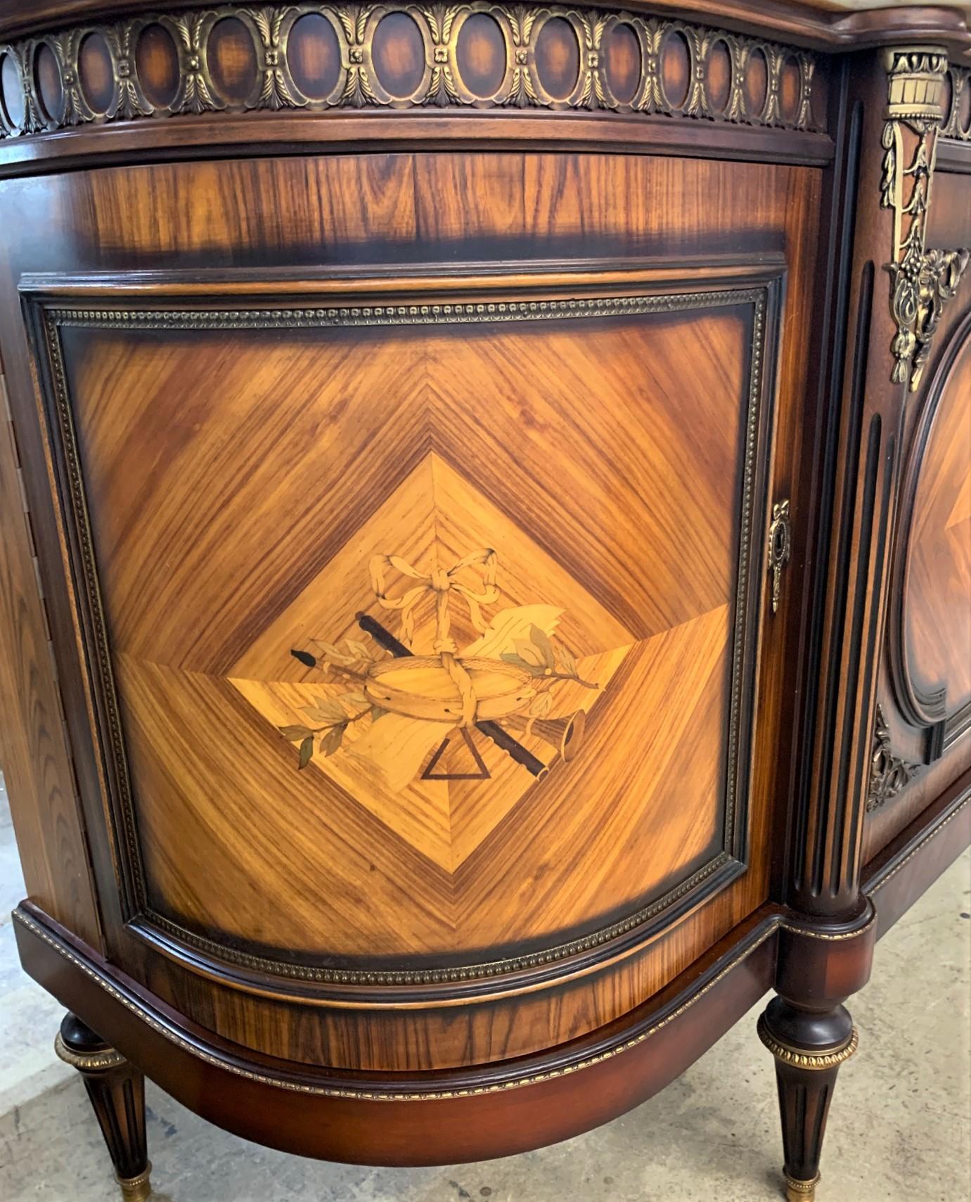 An exceptional quality Spanish sideboard in the Louis XVI manner. Crafted of Fine kingwood and rosewood veneers and featuring detailed marquetry inlays of musical instruments held by a knotted ribbon. The left cupboard door opens to reveal a column