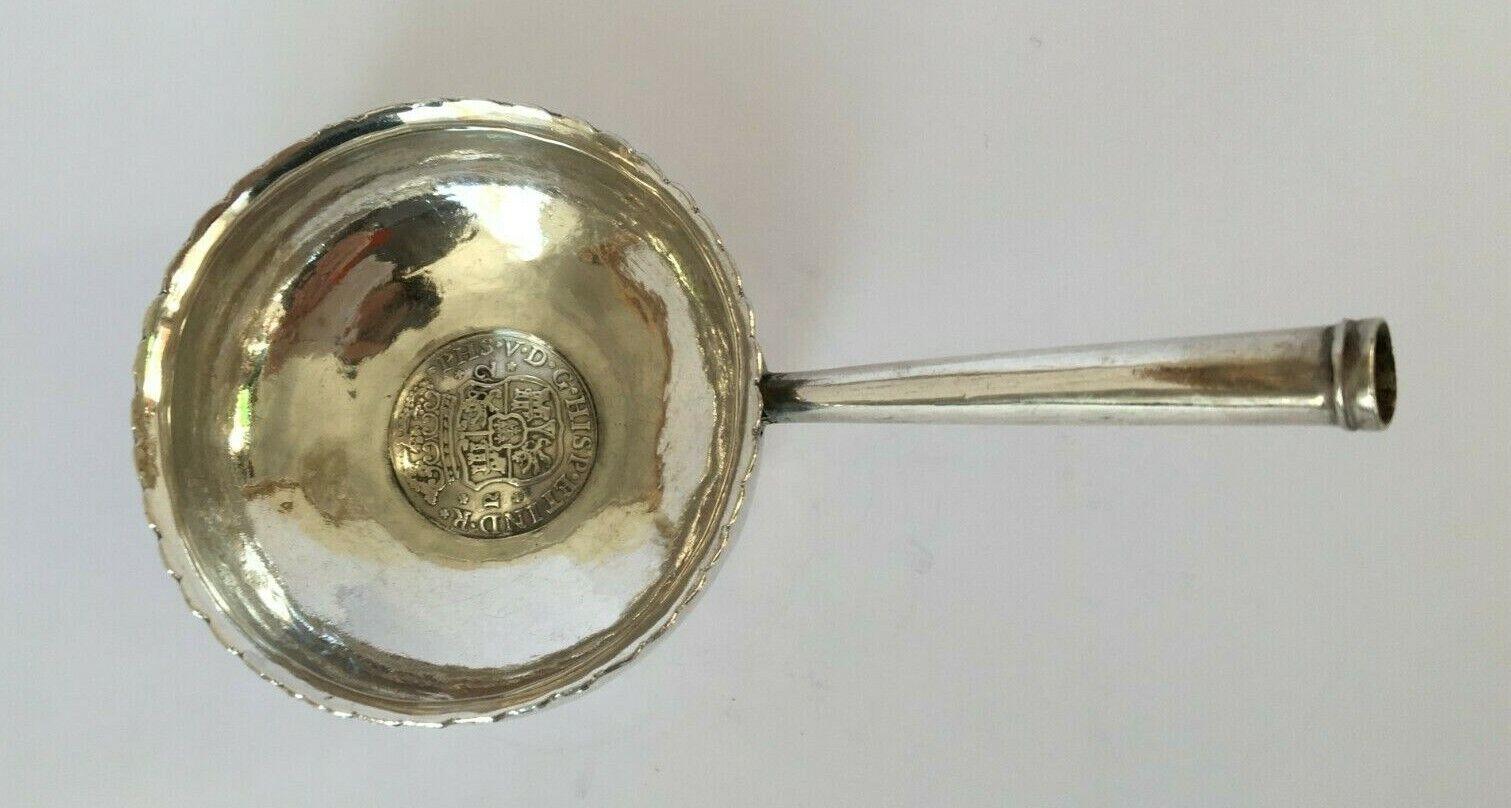 In good condition. This rare and unusual piece was used for tasting wine. It has a coin in the centre:

Obverse
Crowned arms shield flanked by value, and legend all around.
Translation: Felipe 5th by the grace of God King of Spain and the