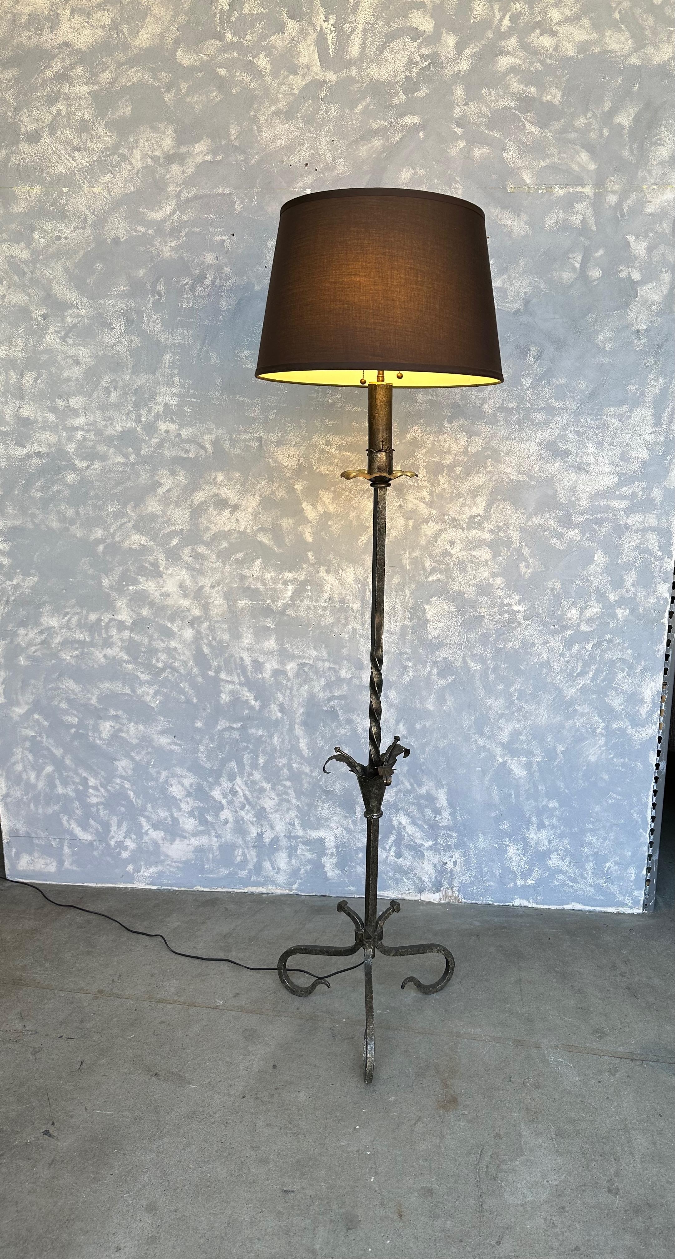 A captivating Spanish silvered iron floor lamp with a scrolled base. This unique piece, crafted in Spain during the 1950s, showcases unparalleled expertise and an exceptional design that will grace your space for years to come. The twisted stem