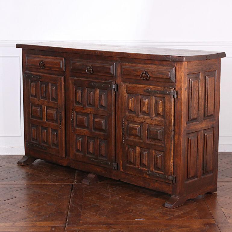 Solid oak Spanish buffet with three paneled doors below three drawers, the top of heavy oak planks, the sides also thickly-paneled. Original wrought iron hardware and a warm rustic patina. C. 1920.



 