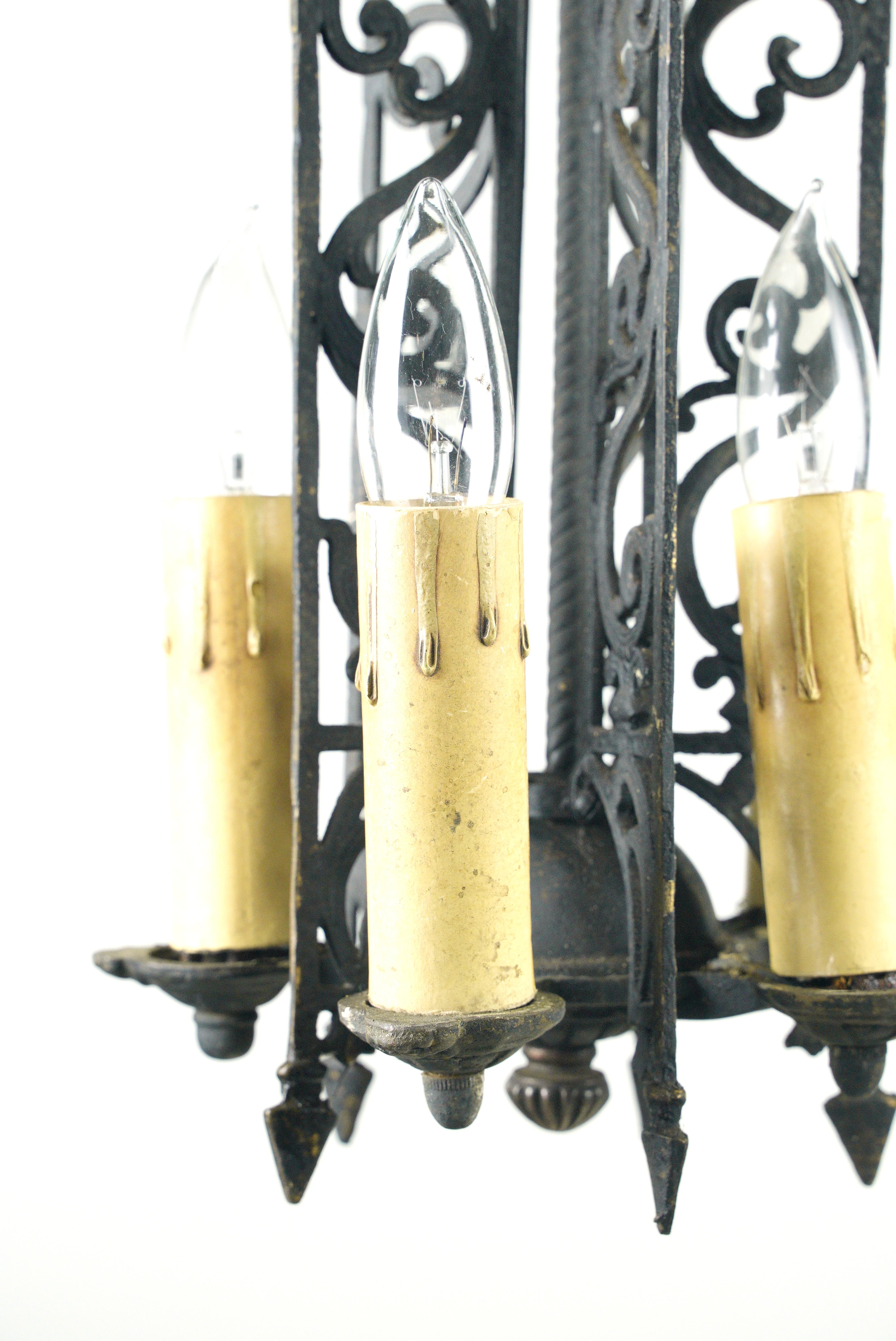 Cette lampe de style espagnol est fabriquée en laiton peint en noir avec des détails tourbillonnants complexes. Illuminez votre espace grâce à ses cinq lampes candélabres apparentes. Ce luminaire est en bon état ancien avec des usures de surface.