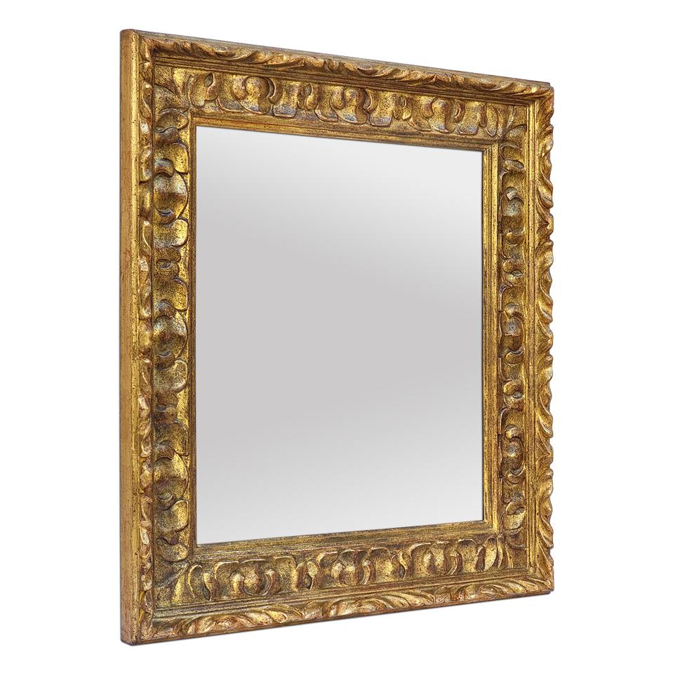 Spanish style carved wood wall mirror, circa 1970. Orned with large stylized acanthus leaves (Antique frame width: 11 cm / 4.33 in.). Leaf gilding patinated. Modern glass mirror. Wood back.