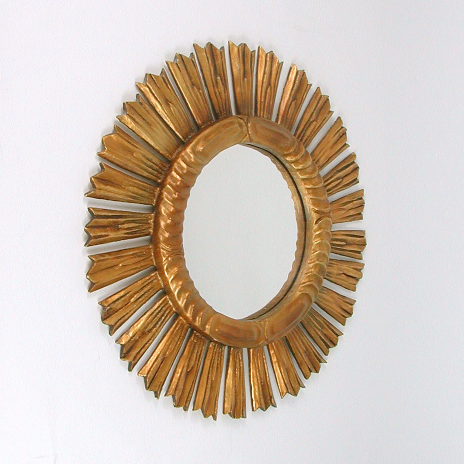 Dieser glamouröse Spiegel aus vergoldetem Holz wurde in den 1940er bis 1950er Jahren in Spanien entworfen und hergestellt. Es hat einen originalen geschnitzten Holzrahmen mit Sonnenschliff und Spiegelglas. Der Rahmen ist in einem sehr guten