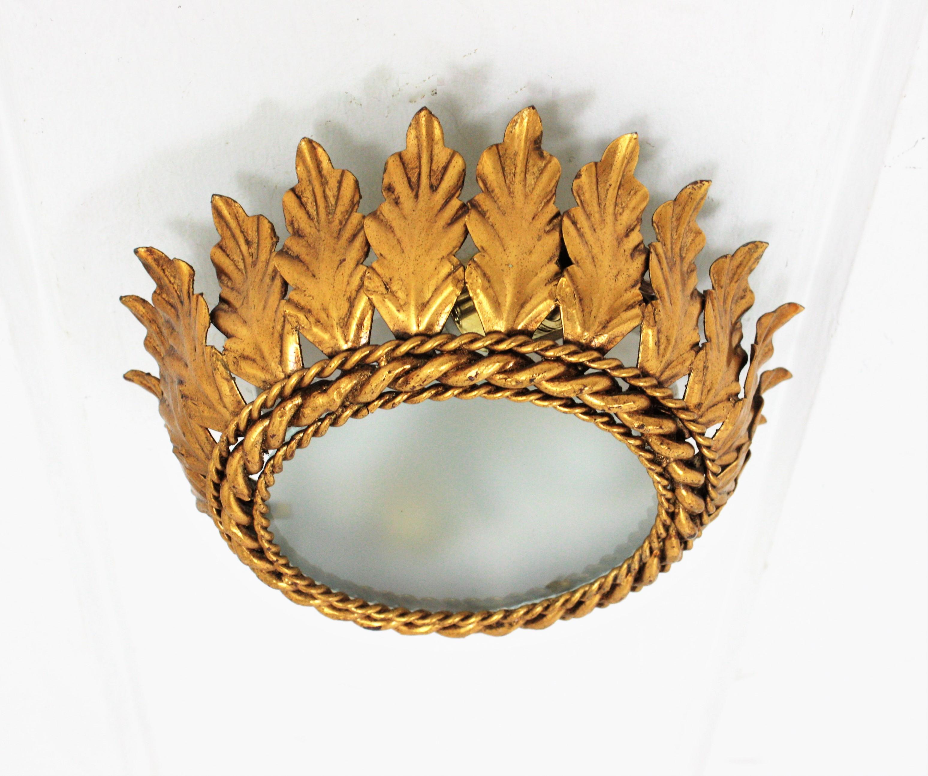 Neoclassical Revival gilt iron leafed crown flush mount with frosted glass shade. Spain, 1940s-1950s.
Handcrafted in Spain at the Mid-Century Modern period in hand-hammered metal with gold leaf gilt finishing. It shows an authentic pretty beautiful