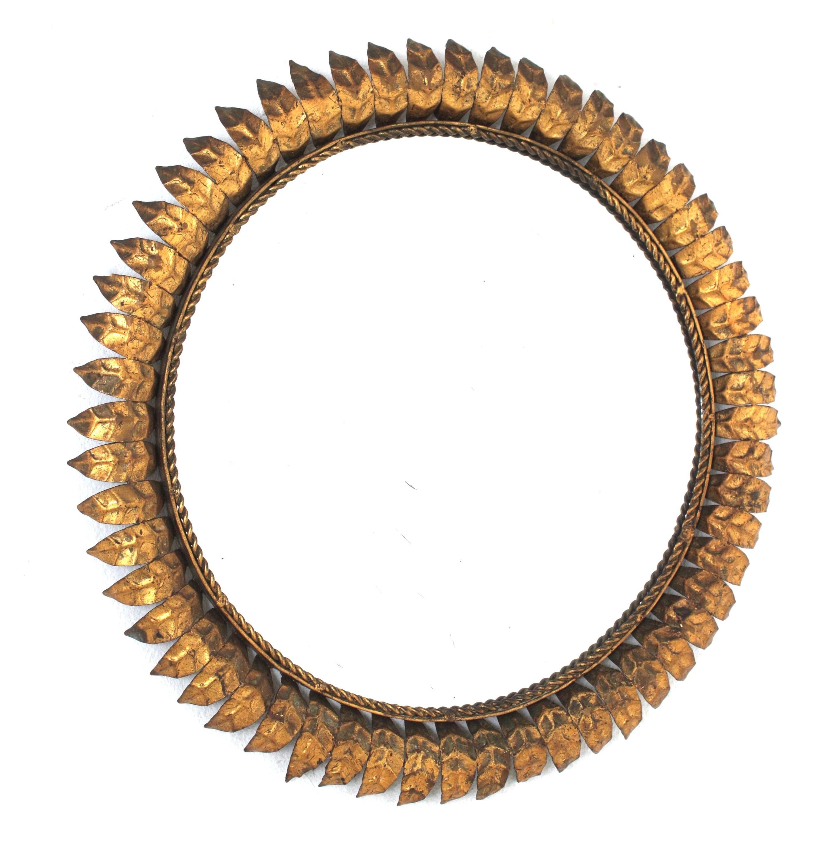 Mid-Century Modern iron sunburst round mirror with leafed frame and gold leaf finish, Spain, 1950s.
This eye-catching leafed sunburst mirror has a very detailed frame, entirely made in gilt iron and showing its original patina and gold leaf