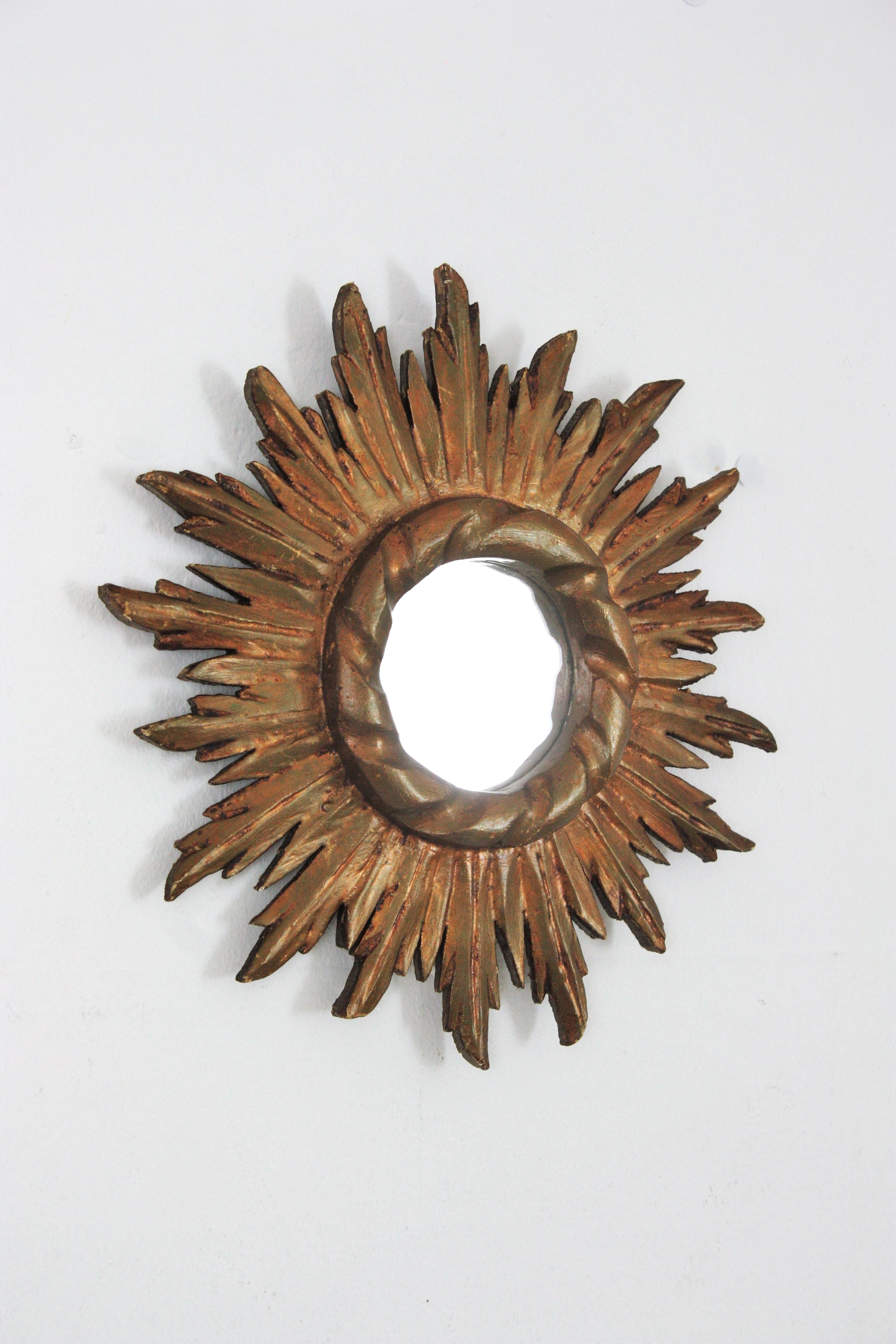 Petit miroir convexe en bois doré sculpté, Espagne,  1950s
Ce miroir en bois sculpté et doré est doté d'un cadre à la patine remarquable qui montre sa dorure à la feuille d'or d'origine dans un ton de dorure bronze foncé.
Placez-le seul ou dans une
