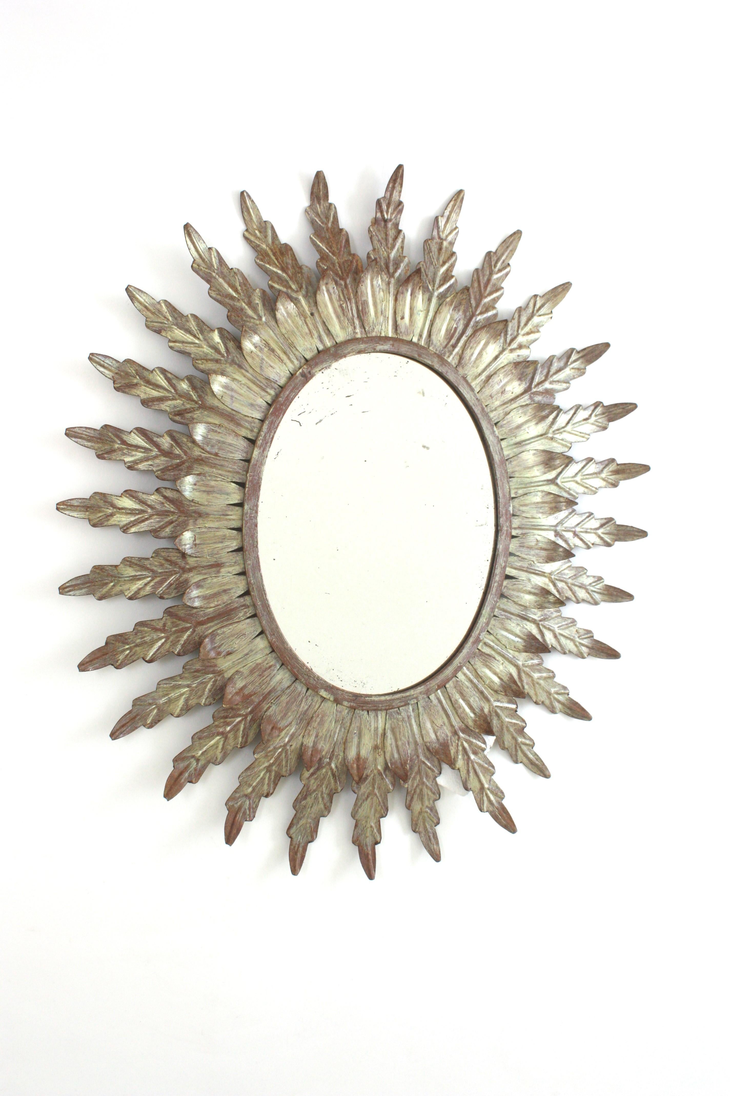 Miroir ovale ensoleillé encadré de feuilles, feuille d'argent, fer patiné, Espagne, années 1950-1960.
Miroir ovale à double couche encadré d'une couche de grandes feuilles de métal et d'une couche de petites feuilles entourant le verre. Dorure