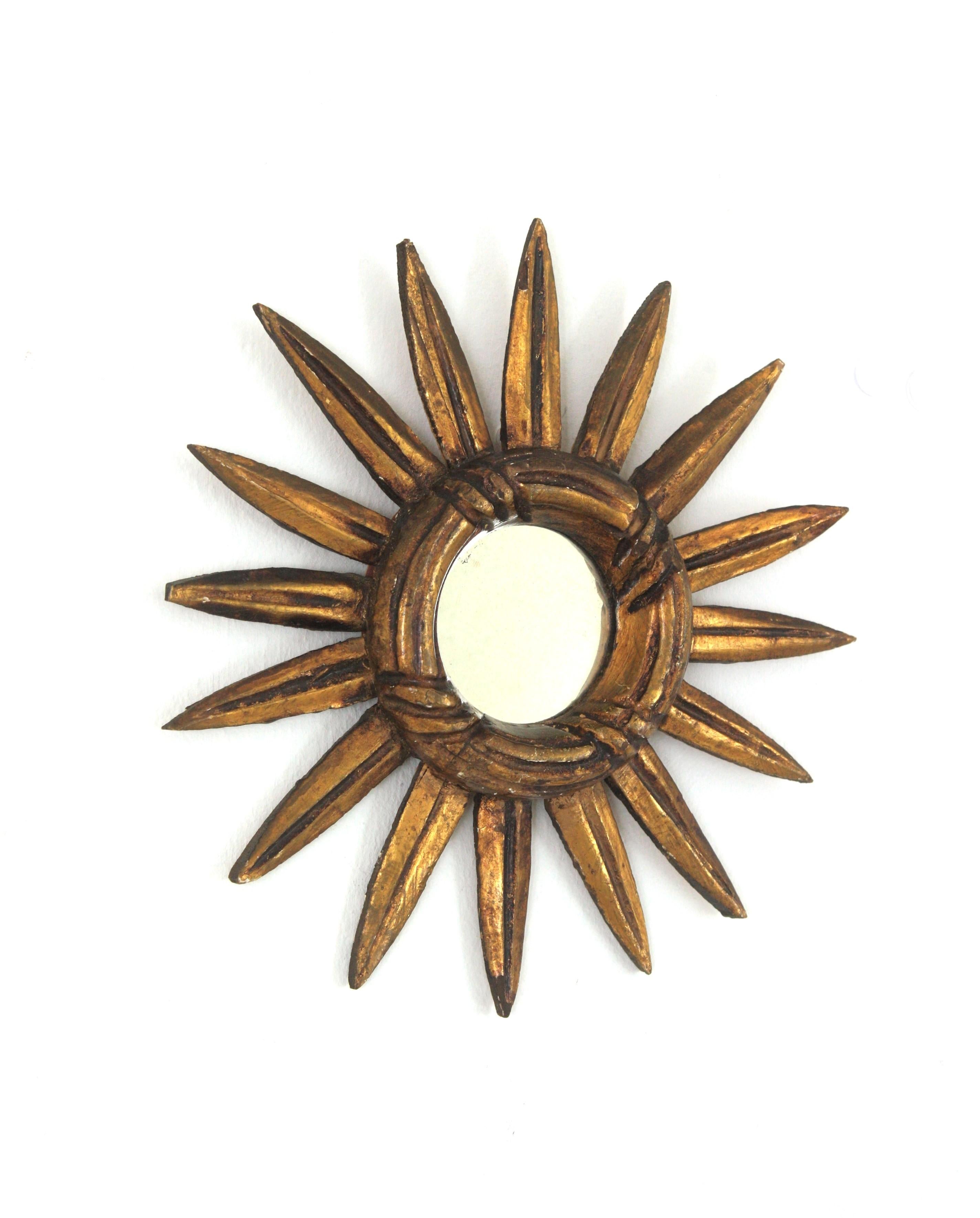 Small scale sunburst mirror in carved giltwood, Spain, 1940-1950s.
Mini sized sunburst mirror in baroque style.
It has a carved ring with stripes and carving details on the rays.
Finished in dark gold leaf gilding and showing a terrific aged