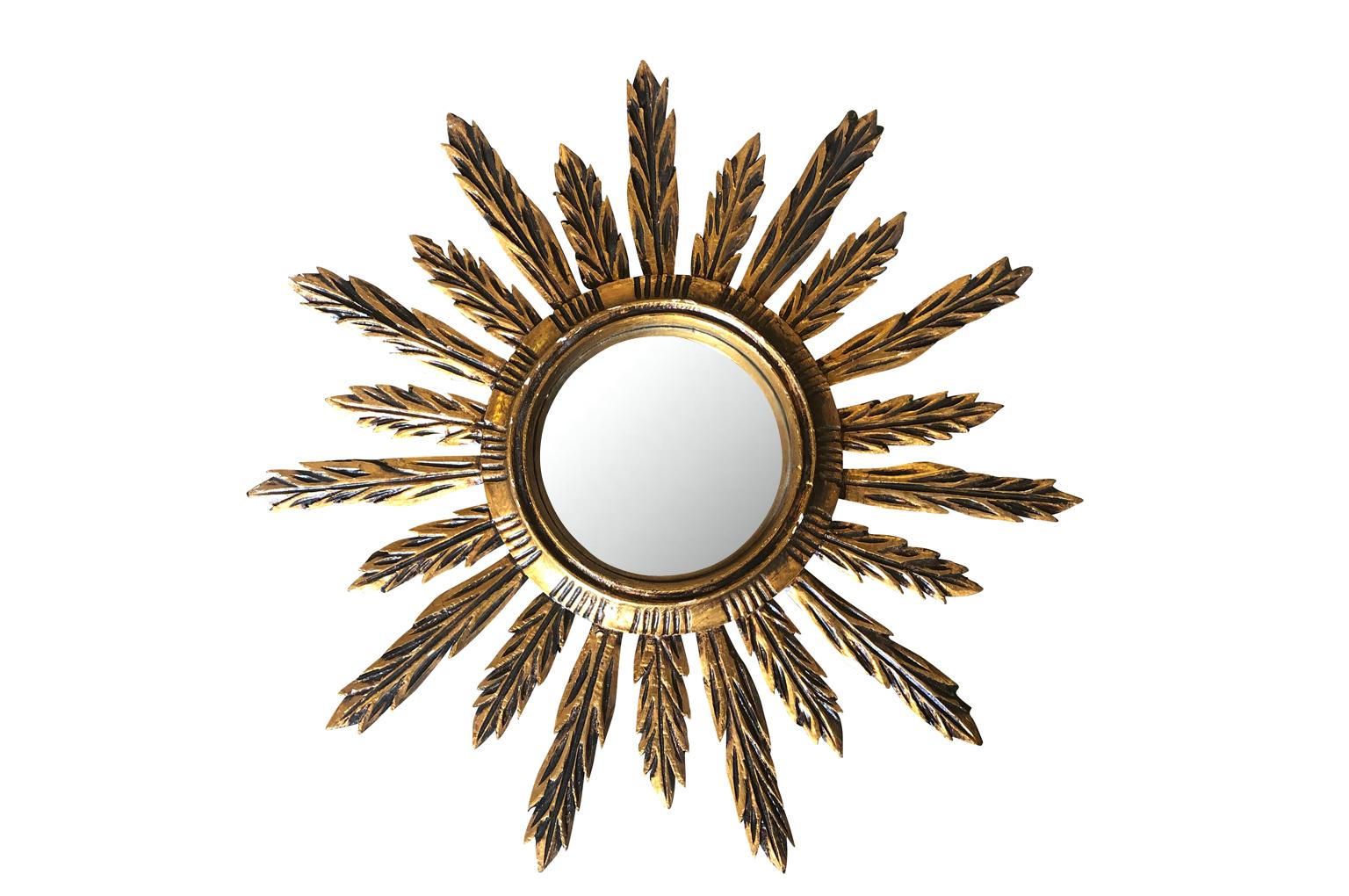 A very lovely Spanish sunburst mirror in hand carved giltwood with its convex mirror. A charming accent piece.