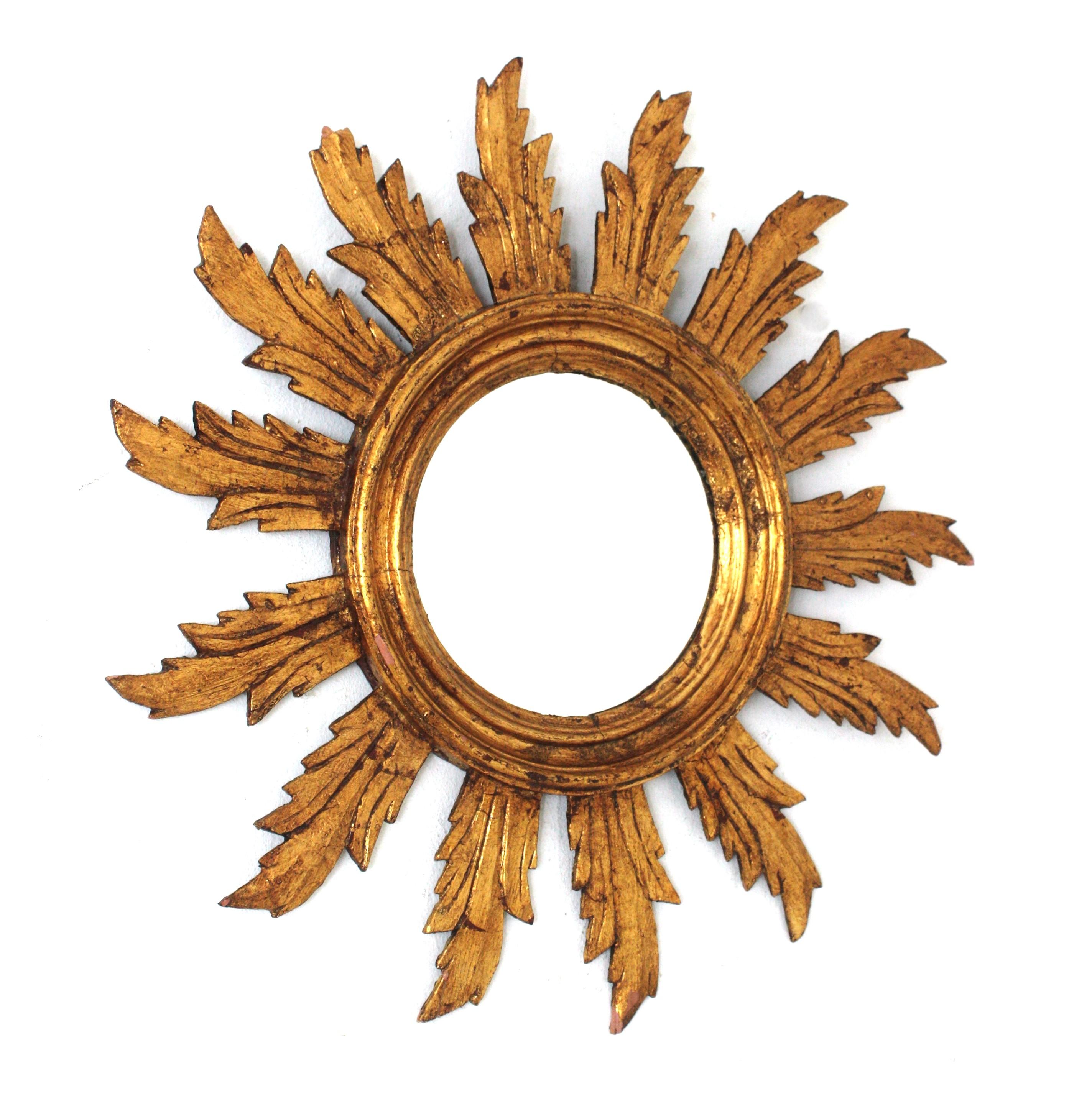 Eye-catching carved giltwood spanish sunburst mirror, 1940s-1950s.
This sunburst mirror features a wood carved round frame surrounding the circular glass. A layer of rays with scalloped details with a central carved ring surrounding the glass. It