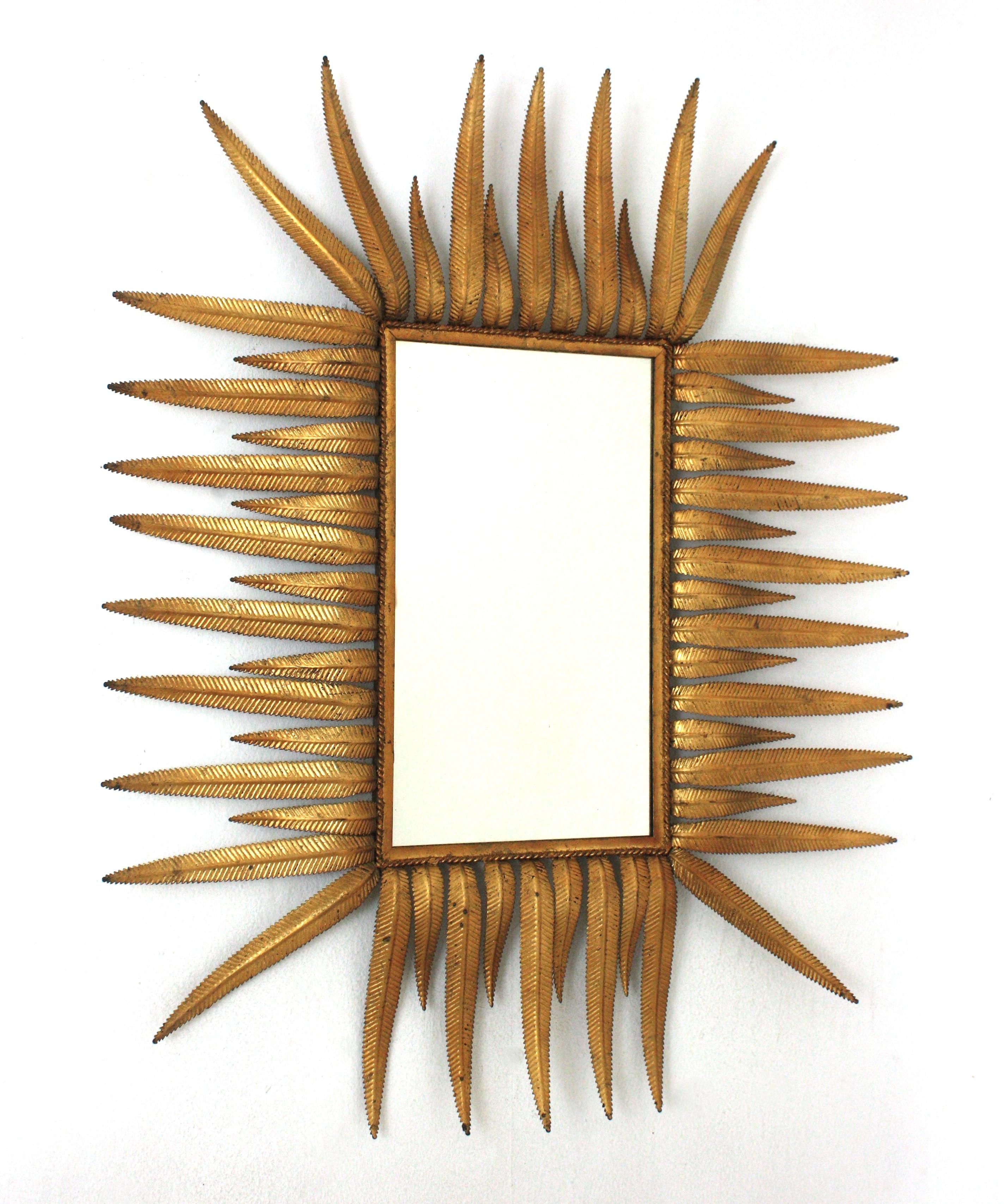 Großer rechteckiger Spiegel mit Sonnenschliff, vergoldetes Eisen, Blattgold
Moderner Sonnenschliff-Wandspiegel aus der Jahrhundertmitte, Spanien, 1960er Jahre
Dieser auffällige Laubspiegel mit Sonnenschliff besteht aus einer Schicht abwechselnd