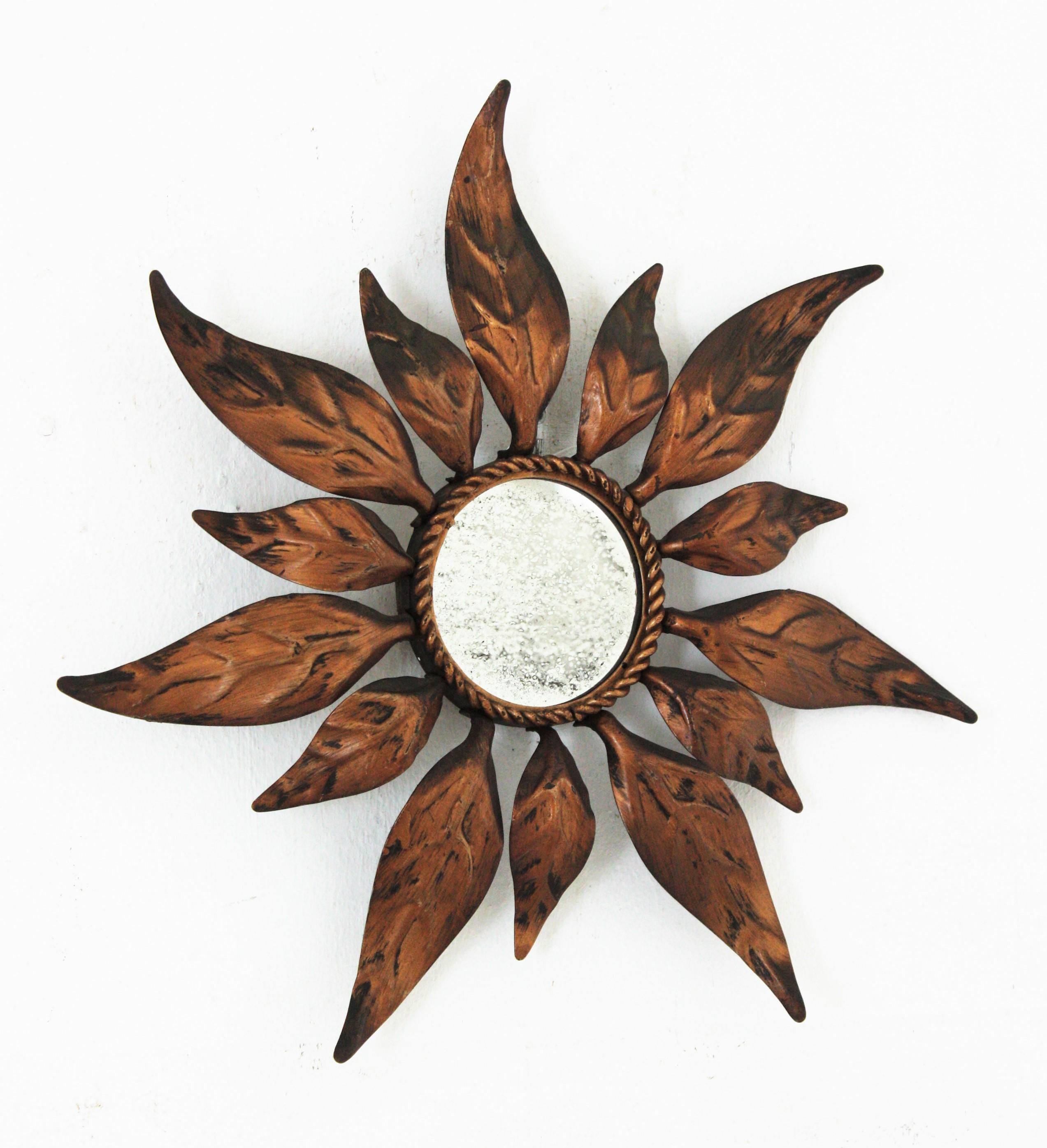 Sunburst leafed mirror in gilt metal, Spain, 1950s
Lovely handcrafted bronze-gilt iron mini sunburst mirror with alternating leaves in two sizes. Terrific aged patina and original mirror glass.
Unusual piece due to its small size. 
Beautiful