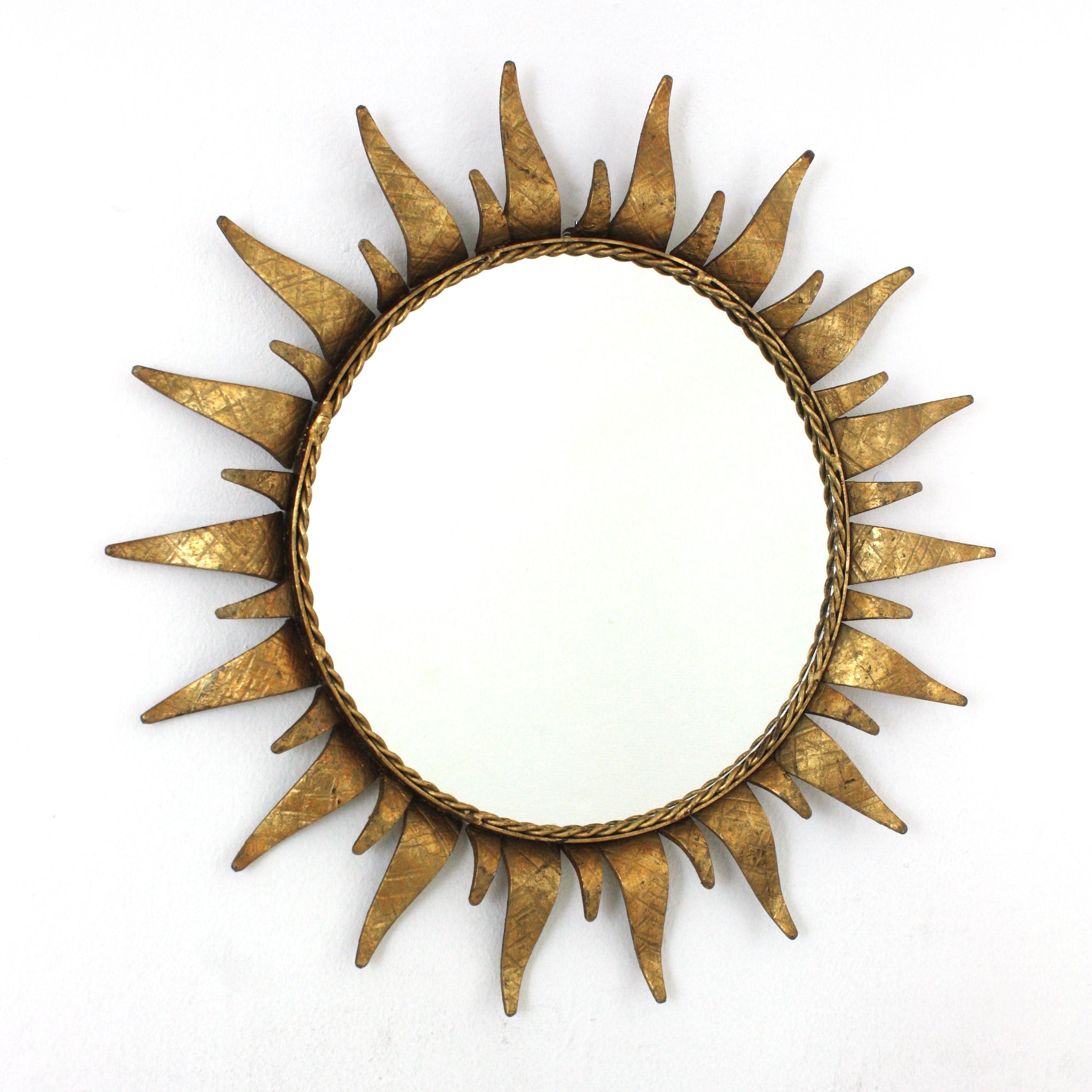 Round Sunburst Mirror in Gold Leaf Gilt Wrought Iron
Mid-Century Modern wrought iron sunburst round wall mirror in gilt iron, Spain, 1950s.
This highly decorative sunburst gilt iron mirror has a nice gilded color and a terrific aged patina showing
