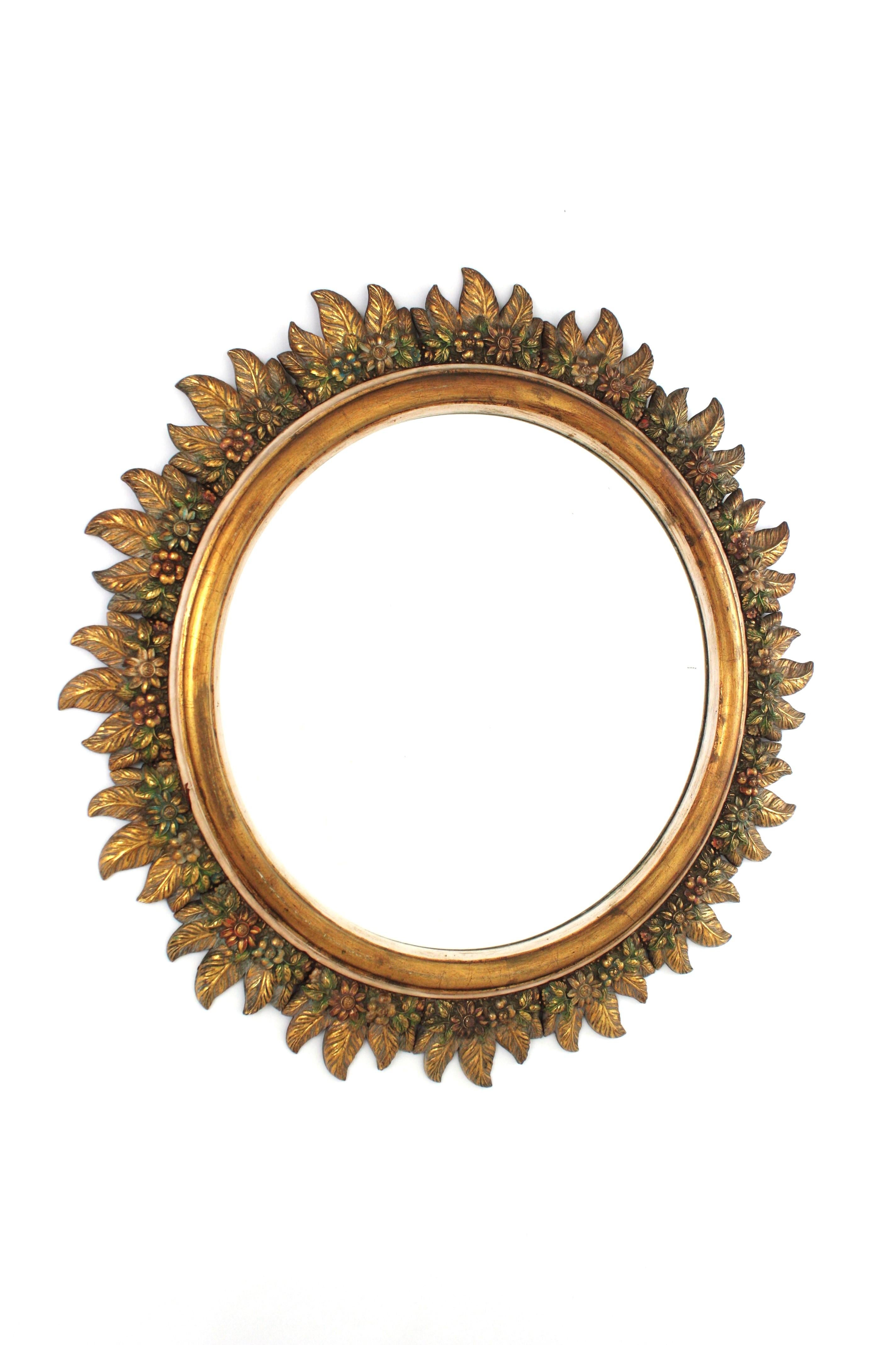 Floral Carved Sunburst Mirror, Giltwood
Handcrafted by Francisco Hurtado, Spain, 1950s
Outstanding polychromed gilded wood sunburst mirror with carved floral foliage frame. 
The frame is richly carved with flowers in different shapes and leaves