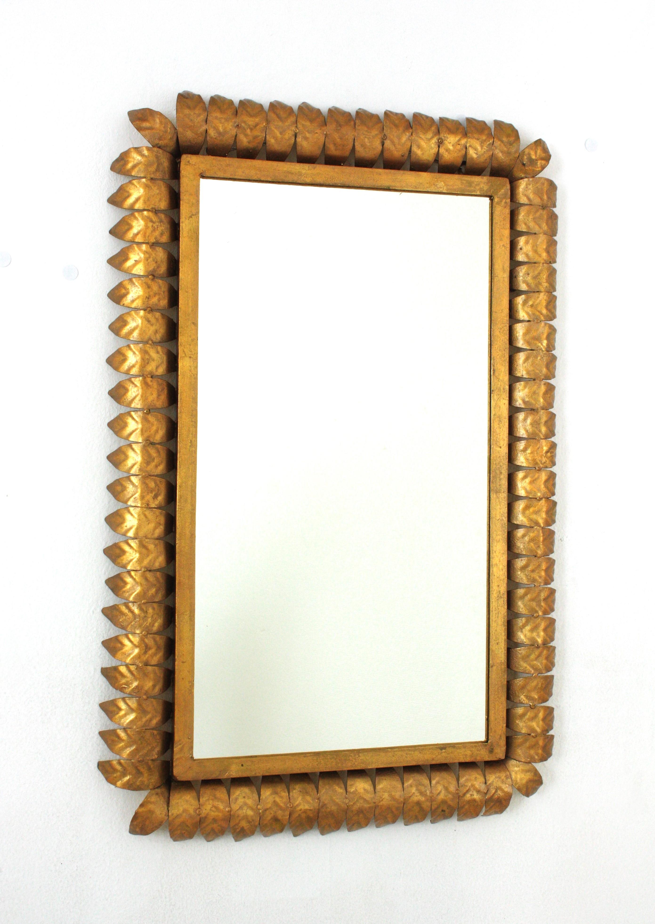 Wrought Gilt iron sunburst rectangular wall mirror with gold leaf finish, Spain, 1950s.
Highly decorative rectangular leaf framed sunburst mirror with gold leaf gilding.
Entirely made by hand. Twisted iron rope and eye-catching jagged edge