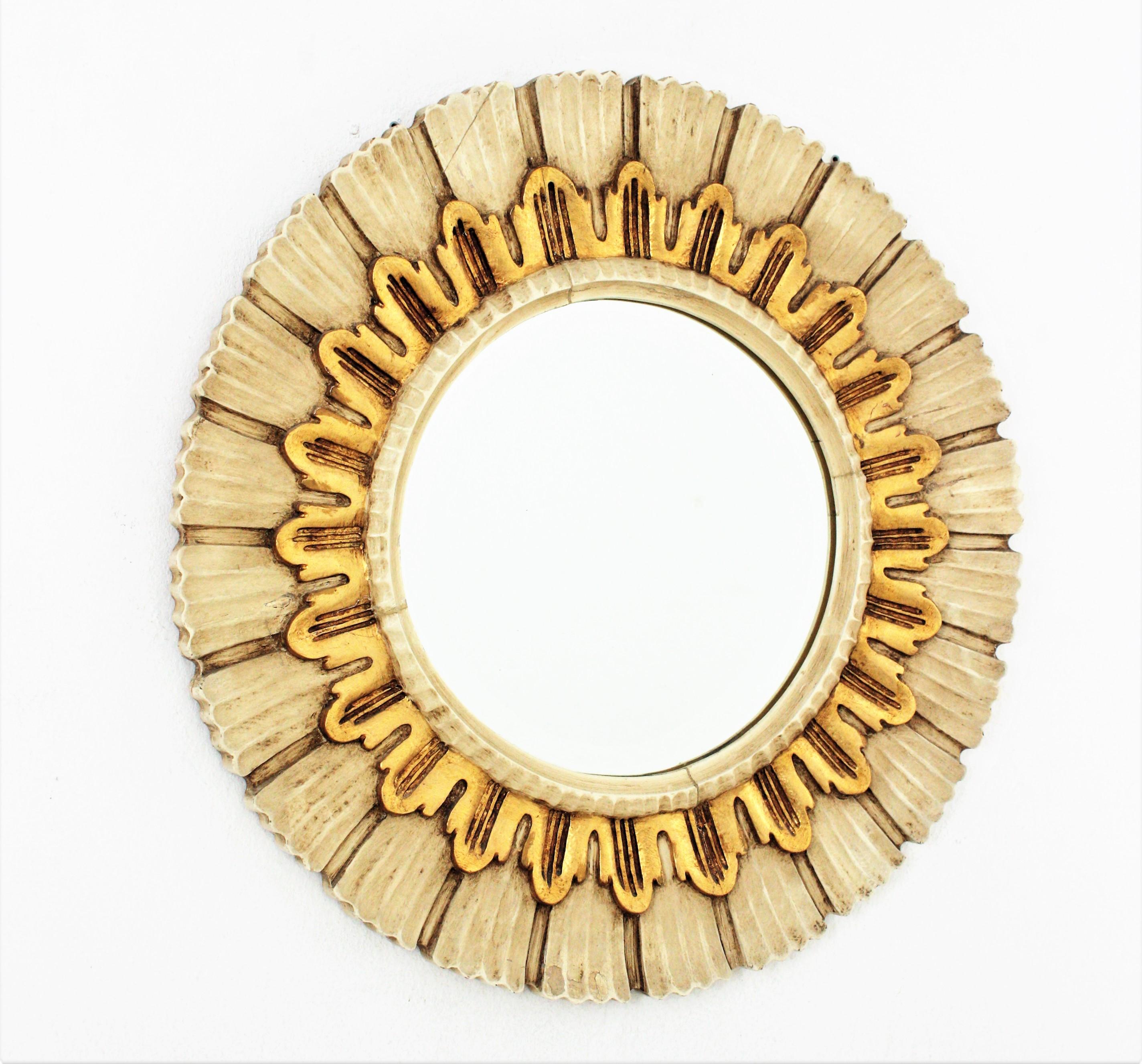 Eye-catching carved and gilded wood round sunburst mirror with beige and gilded wooden frame.Spain, 1960s.
Carved wood and gold leaf gilding. The beige patinated frame has striped carving details and a layer of giltwood surrounding the glass. The