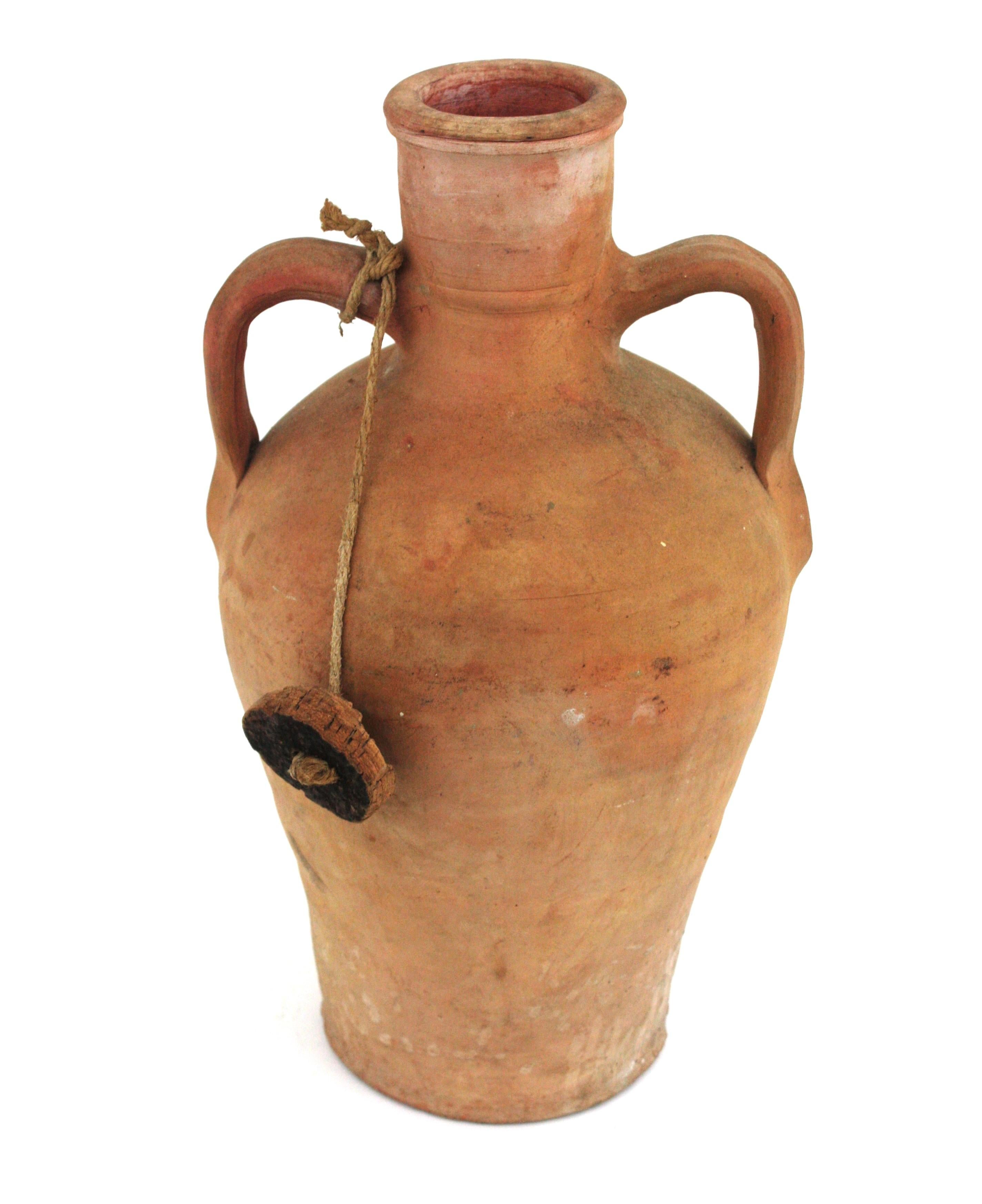 Handmade terracotta two-handled water jar with cork lid, Spain 1930s-1940s.
Traditional Spanish terracotta pitcher. Unglazed exterior and interior with handles at both sides. Used as water container. 
Use it as decorative vessel to add a natural