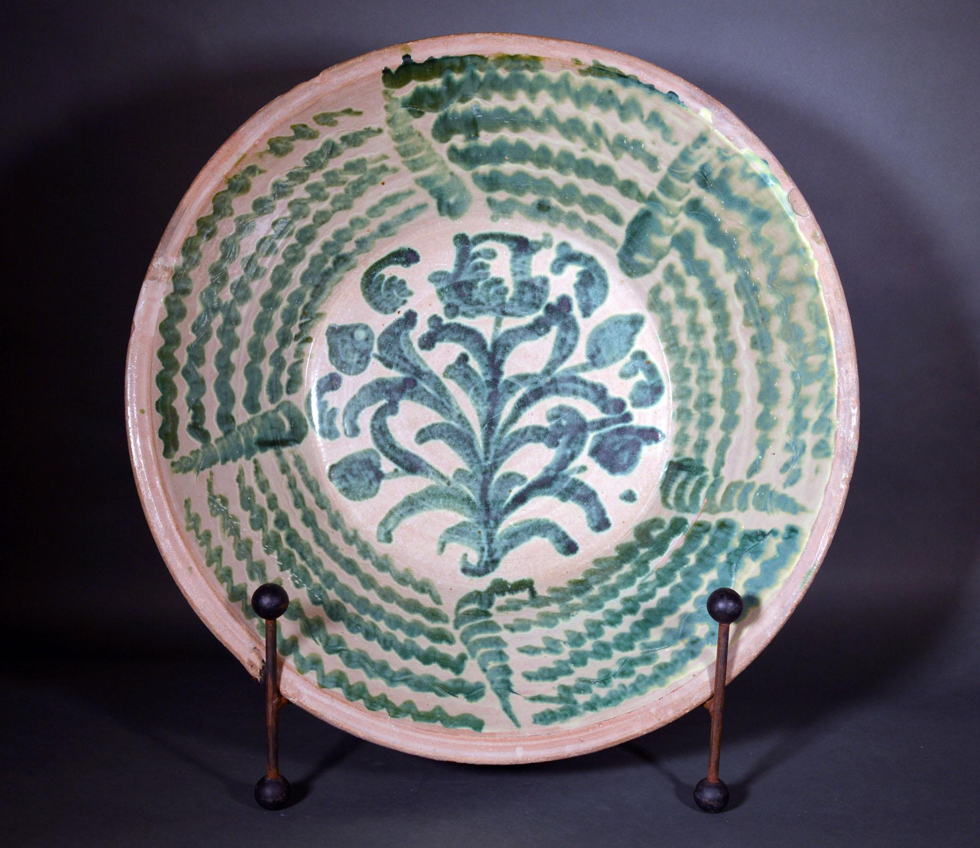 Spanish tin-glazed earthenware pottery oversized basin or lebrillo,
Fajalauza, Granada,
19th century


The massive circular deep circular basin or Librillo with slightly flaring sides is glazed and robustly decorated on the interior with green