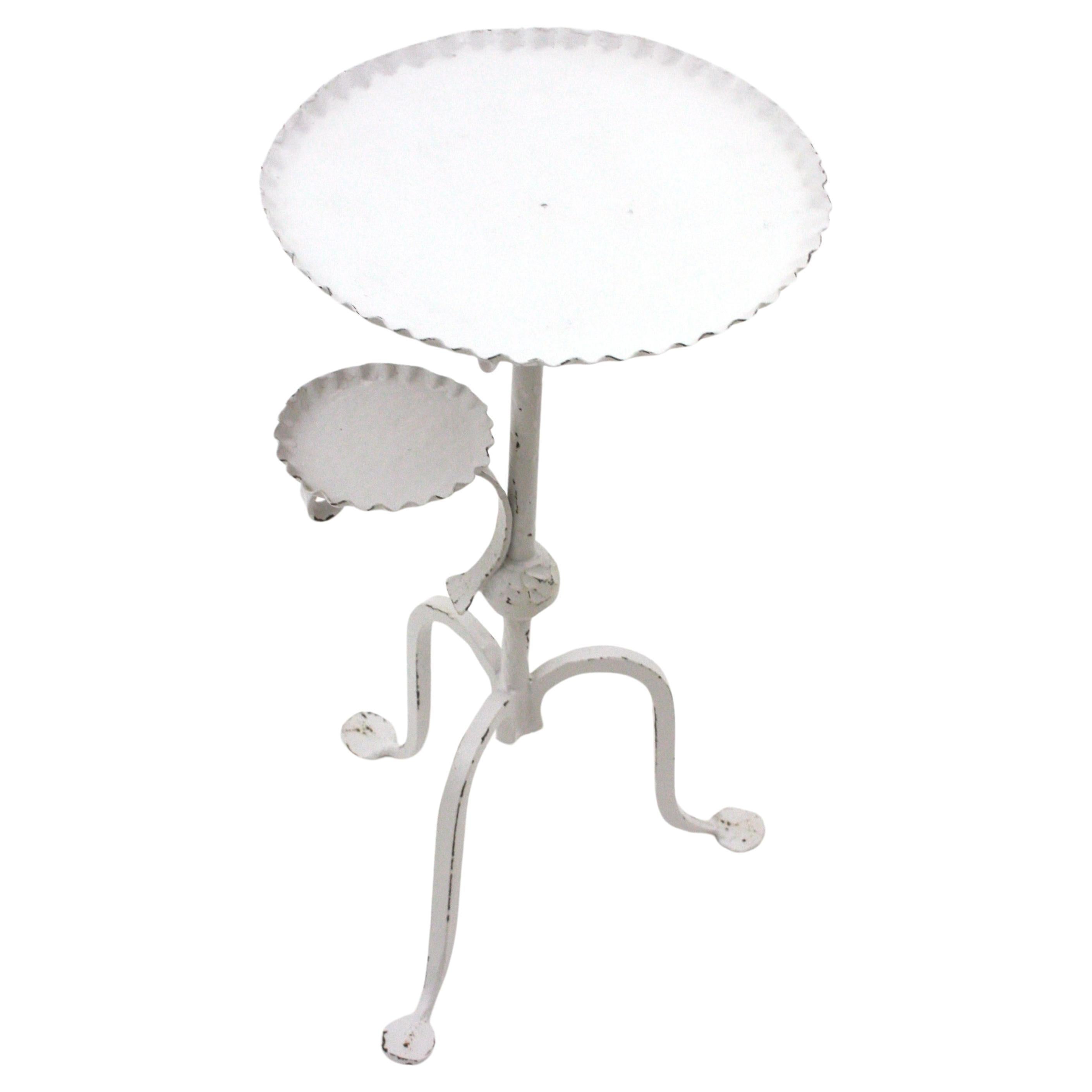 Table d'appoint unique en fer forgé patiné blanc avec cendrier. Espagne, années 1940-1950.
Cette élégante table en fer forgé à la main présente un plateau rond à bord ondulé reposant sur une base tripode. La tige est ornée d'une boule. Il présente